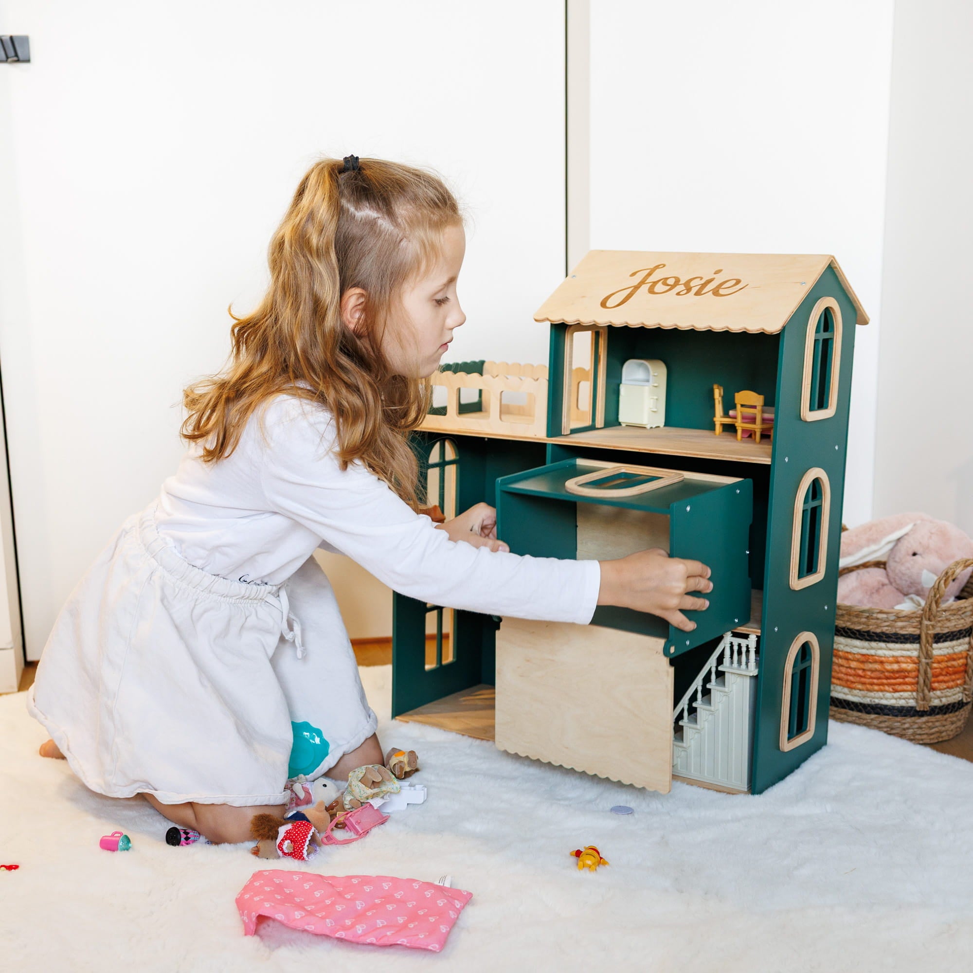 The dollhouse is dark green with light natural wood