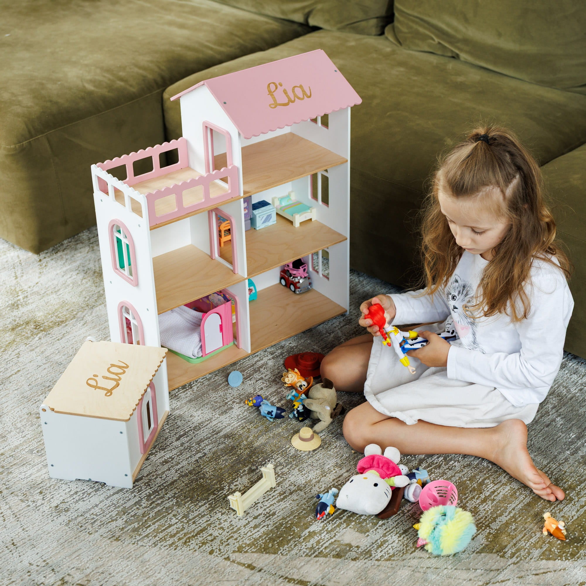 The dollhouse is custom-painted with the name 'Lia' on the roof and top of the box.