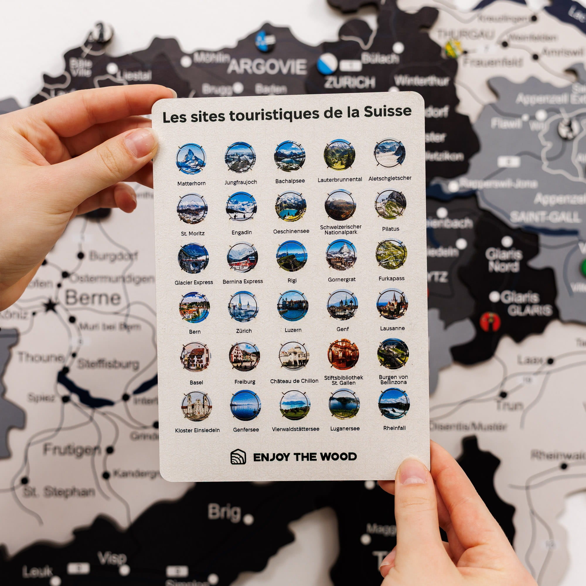 Card with Swiss tourist sites icons held over a map of Switzerland