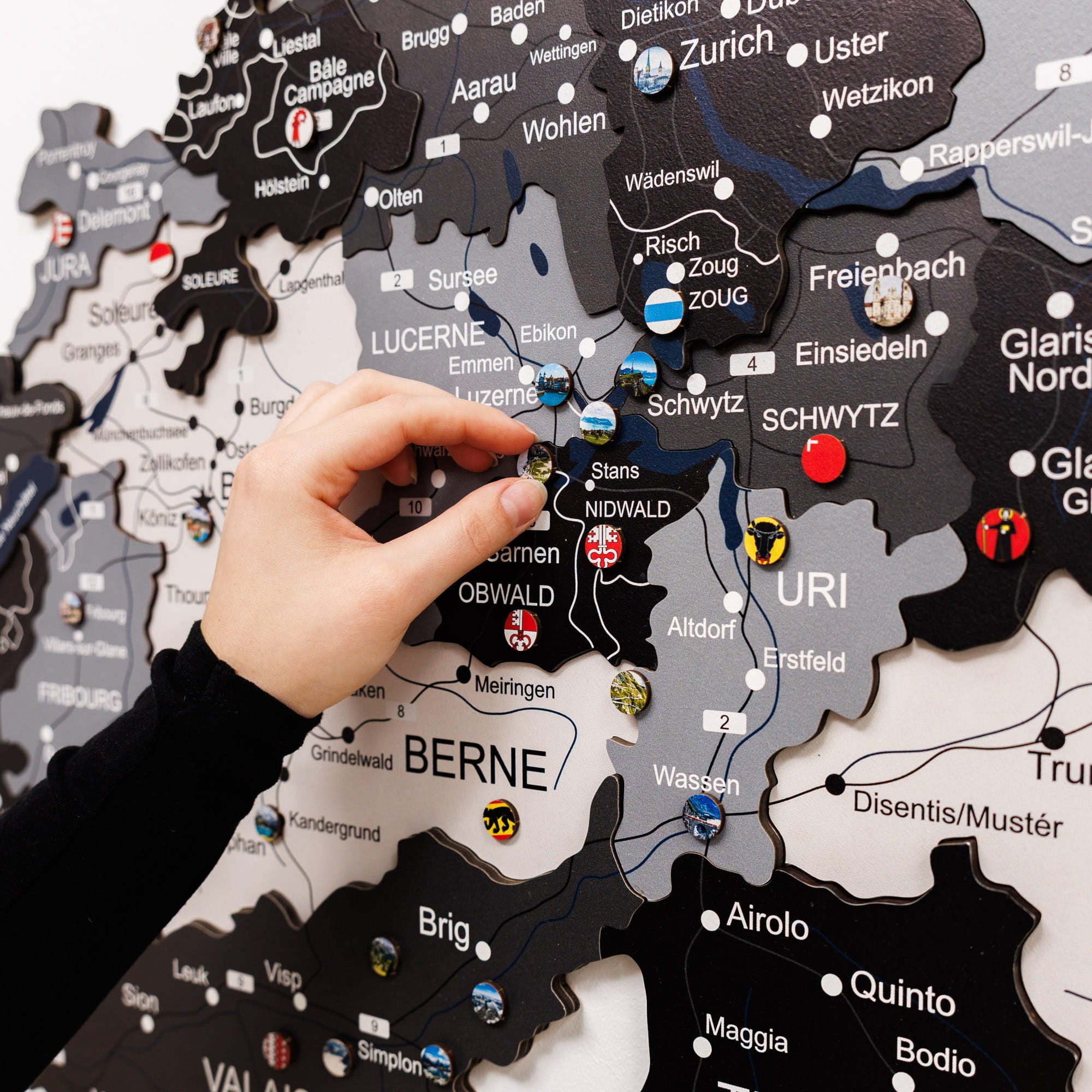 Hand interacting with a map of Switzerland featuring cantonal flags.