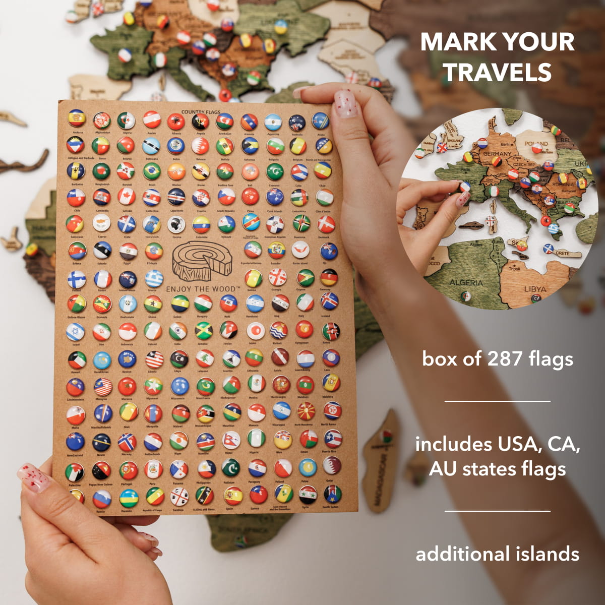 A person holds a wooden travel flag board covered with many small colorful country flags. The image includes text reading 'MARK YOUR TRAVELS,' 'box of 287 flags,' 'includes USA, CA, AU states flags,' and 'additional islands,' plus a circular inset showing hands placing flags on a wooden world map.