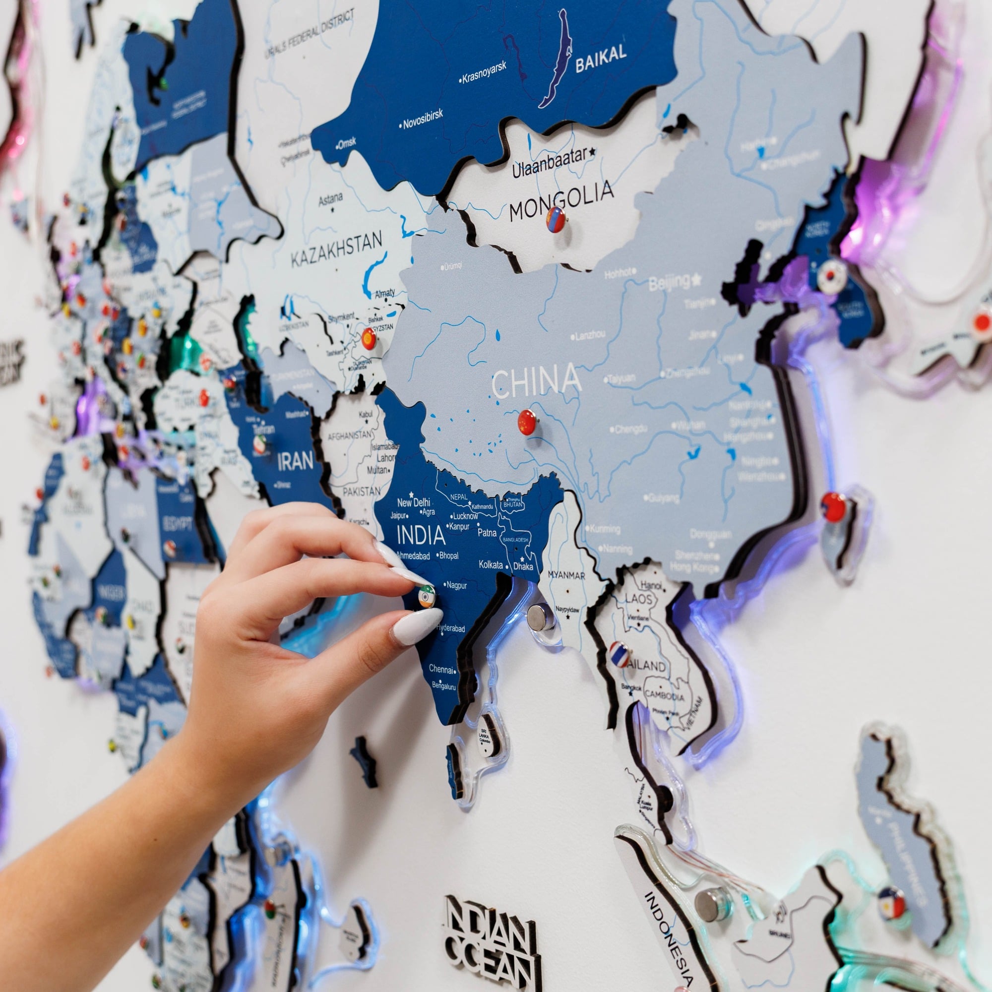 Hand interacting with a world map display on a wall.