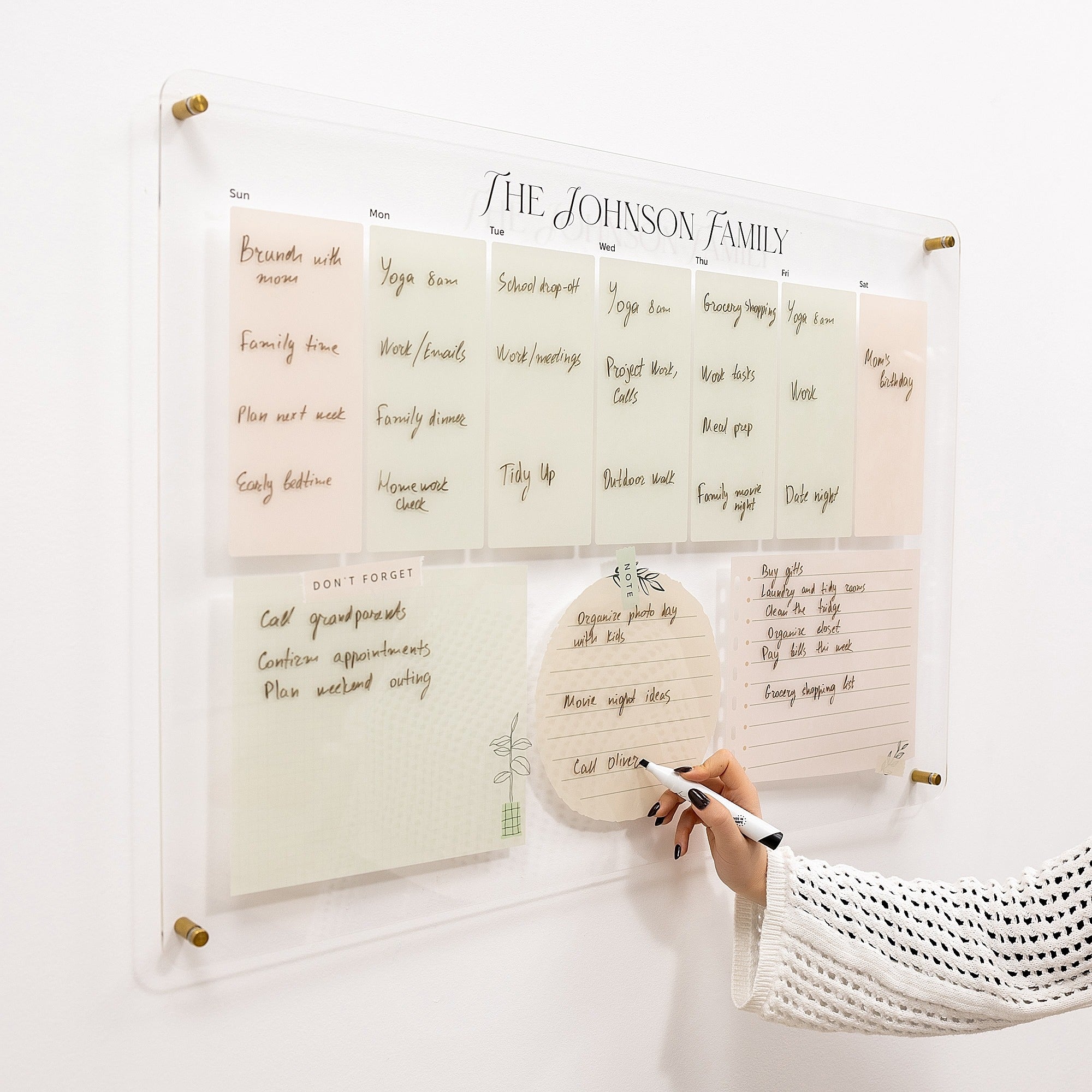 Family schedule chart on a wall with a hand holding a pen.