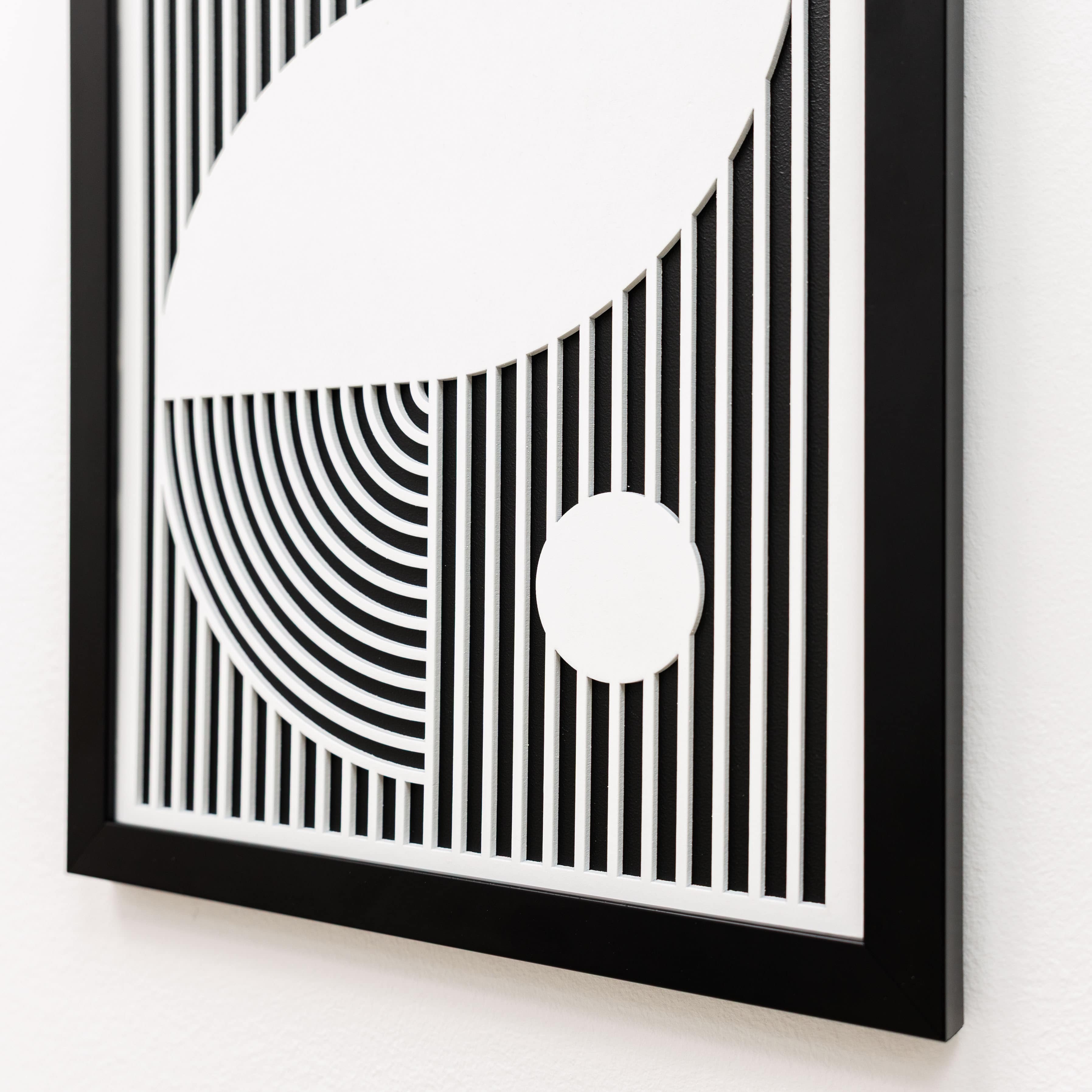 Framed black and white abstract art piece on a white wall