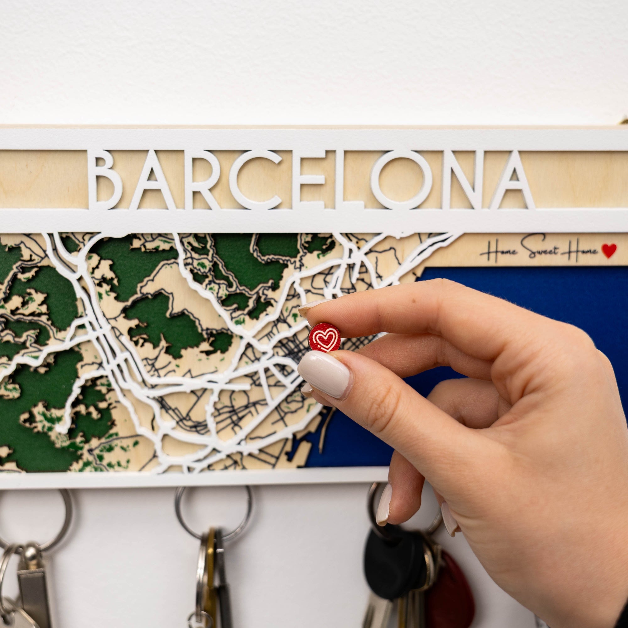 Map of Barcelona with a hand holding a red heart keychain against a white background