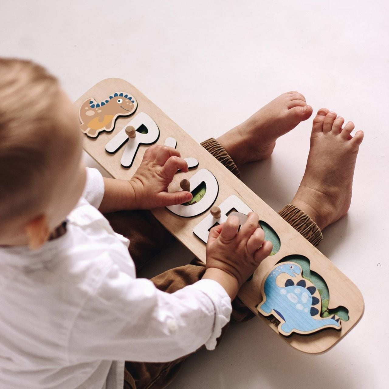 Child playing with a wooden puzzle toy on a white surface