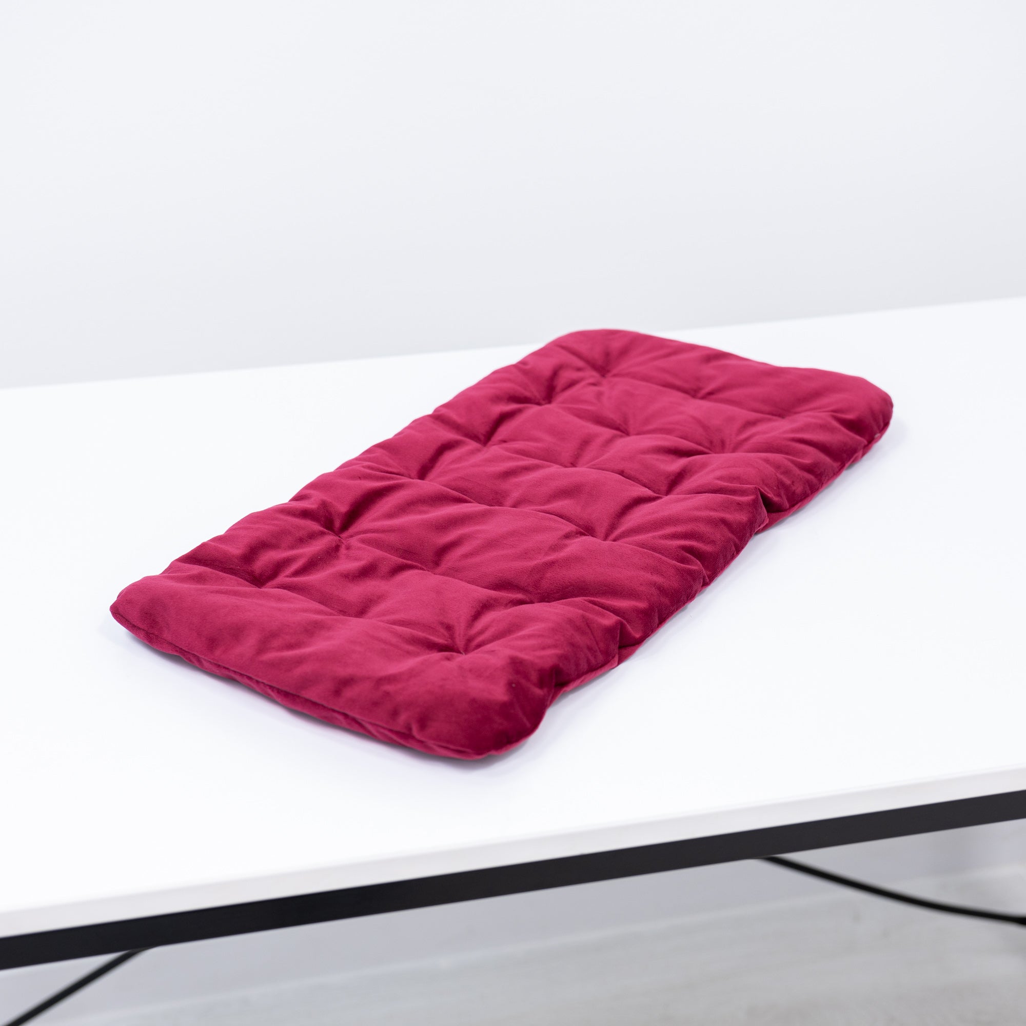 Pink quilted mat on a white surface with a light gray background