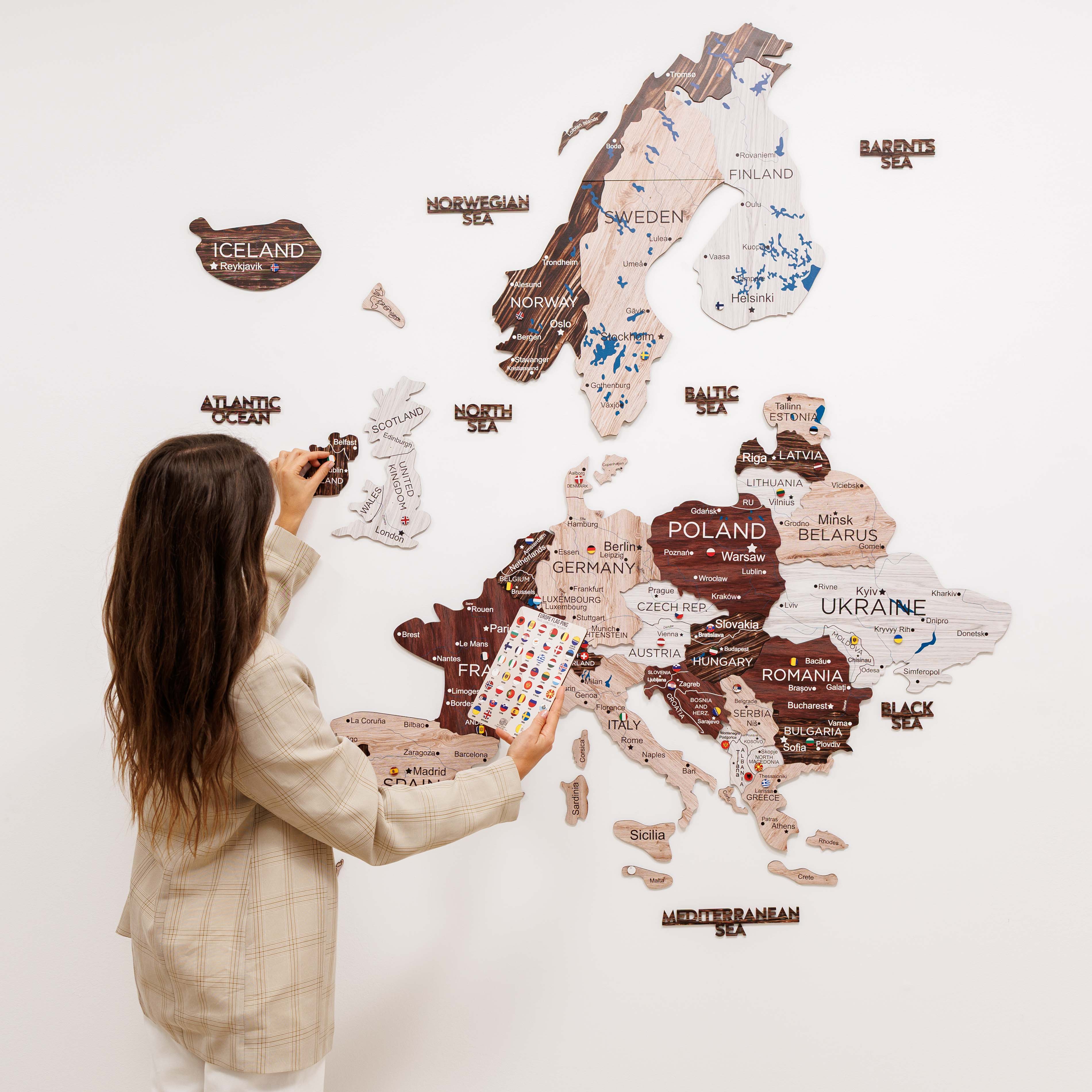 Woman taking a photo of a wall with a decorative map of Europe.