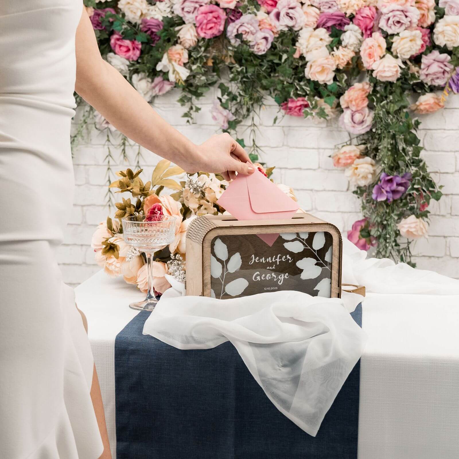 Bride placing envelope into personalized wooden wedding card box