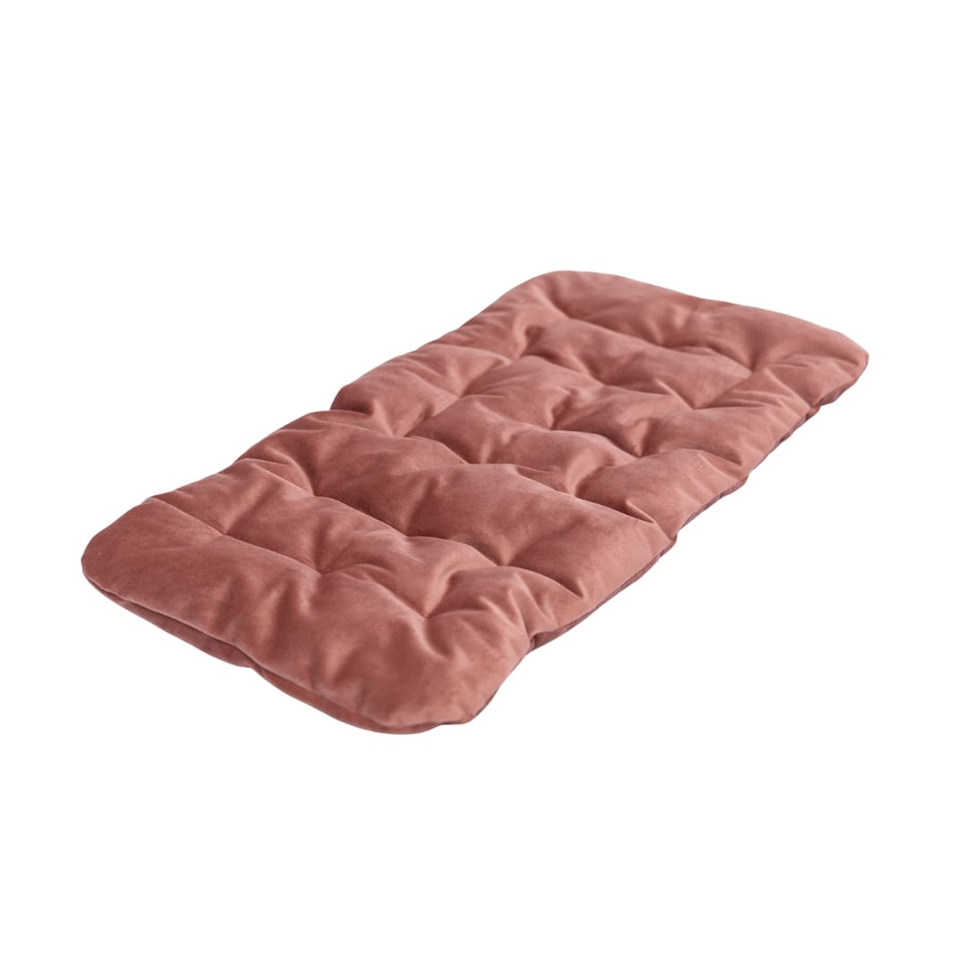 Pink quilted mat on a white surface with a light gray background