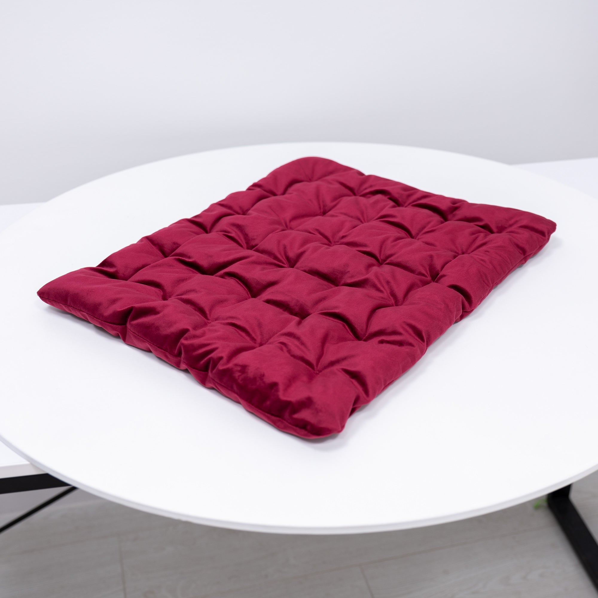 Red quilted cushion on a white round table
