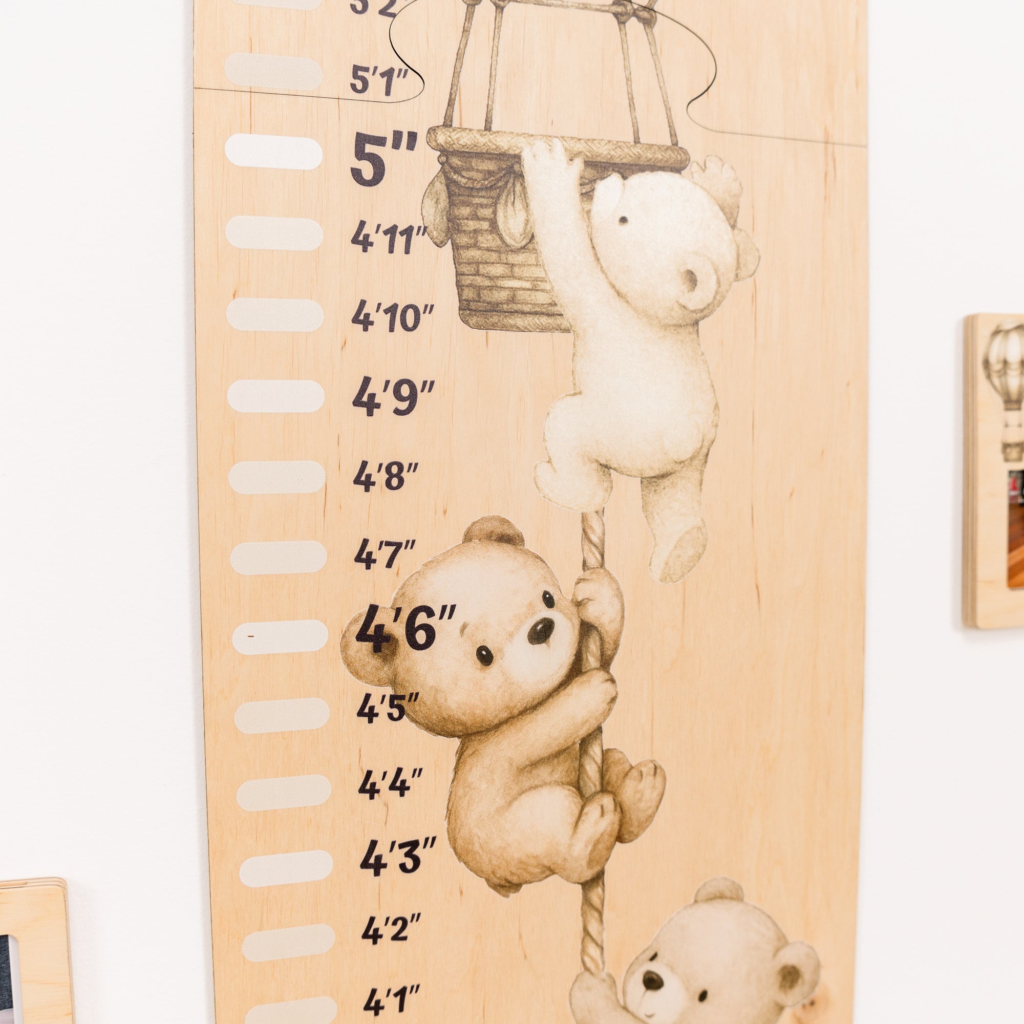 Wooden growth chart with teddy bear design on a white wall.
