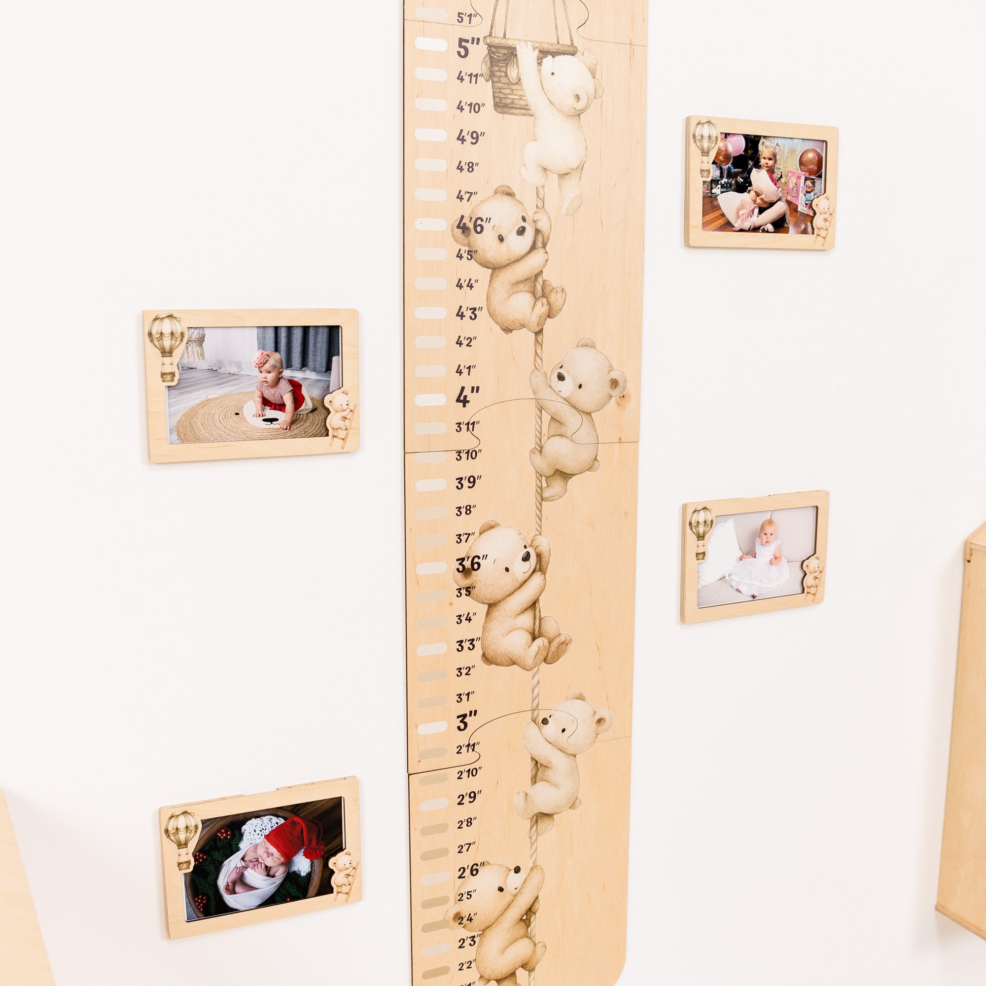 Wooden growth chart with teddy bear figures and photo frames on a white wall.