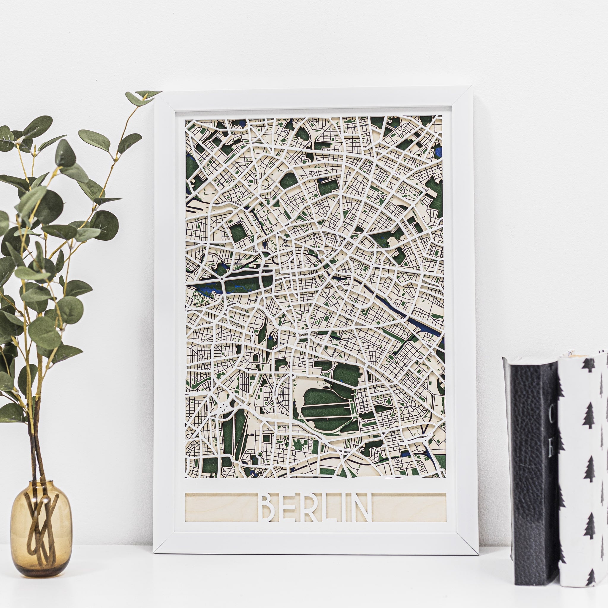 Framed map of Berlin on a white wall with decorative elements.