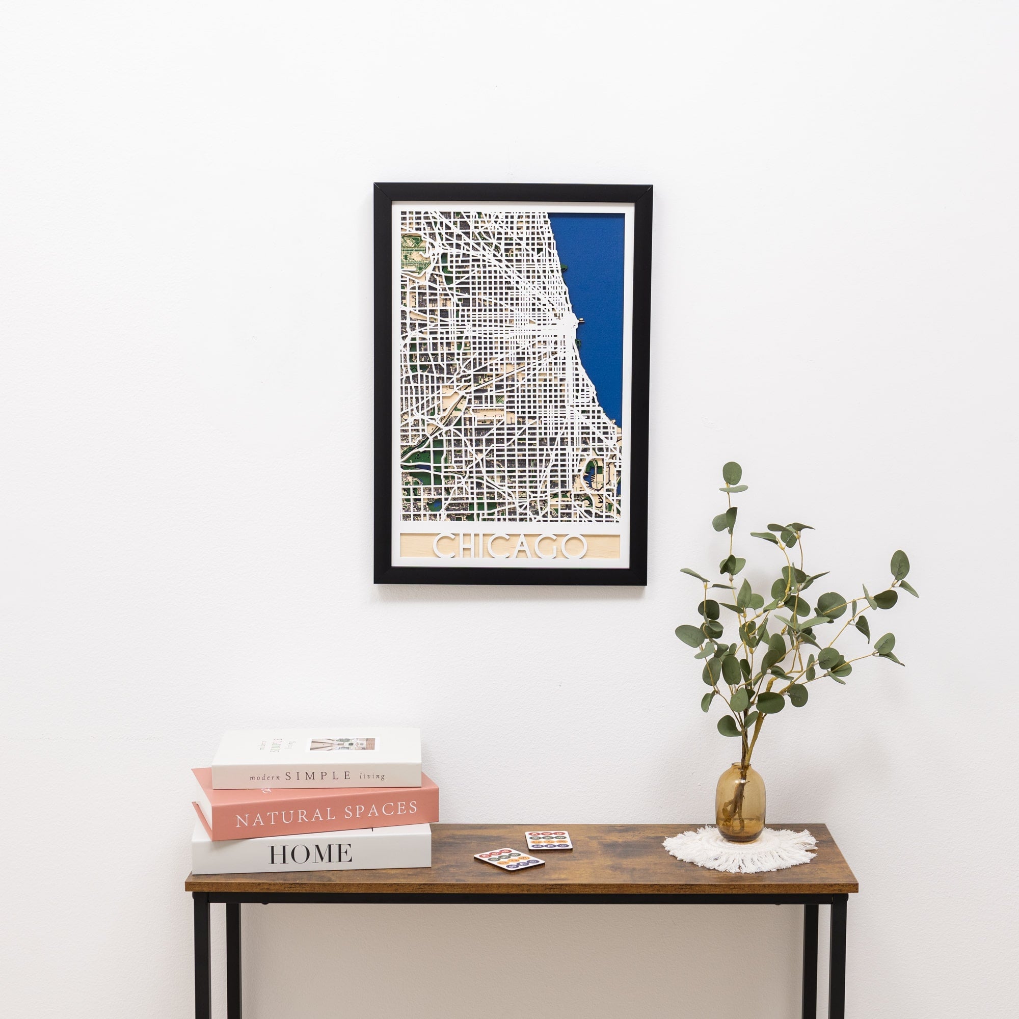 Framed map of Chicago on a wall above a wooden table with books and a plant.