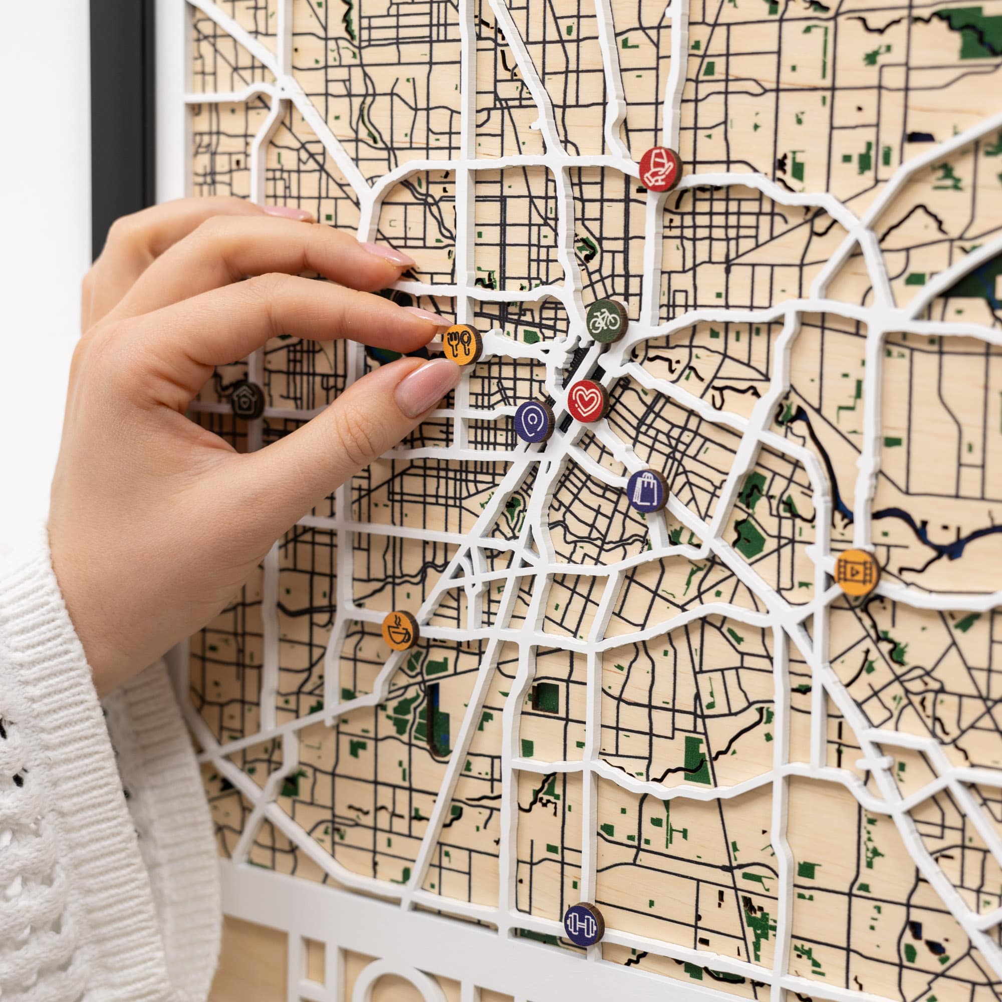 Hand placing a decorative pin on a map with various icons