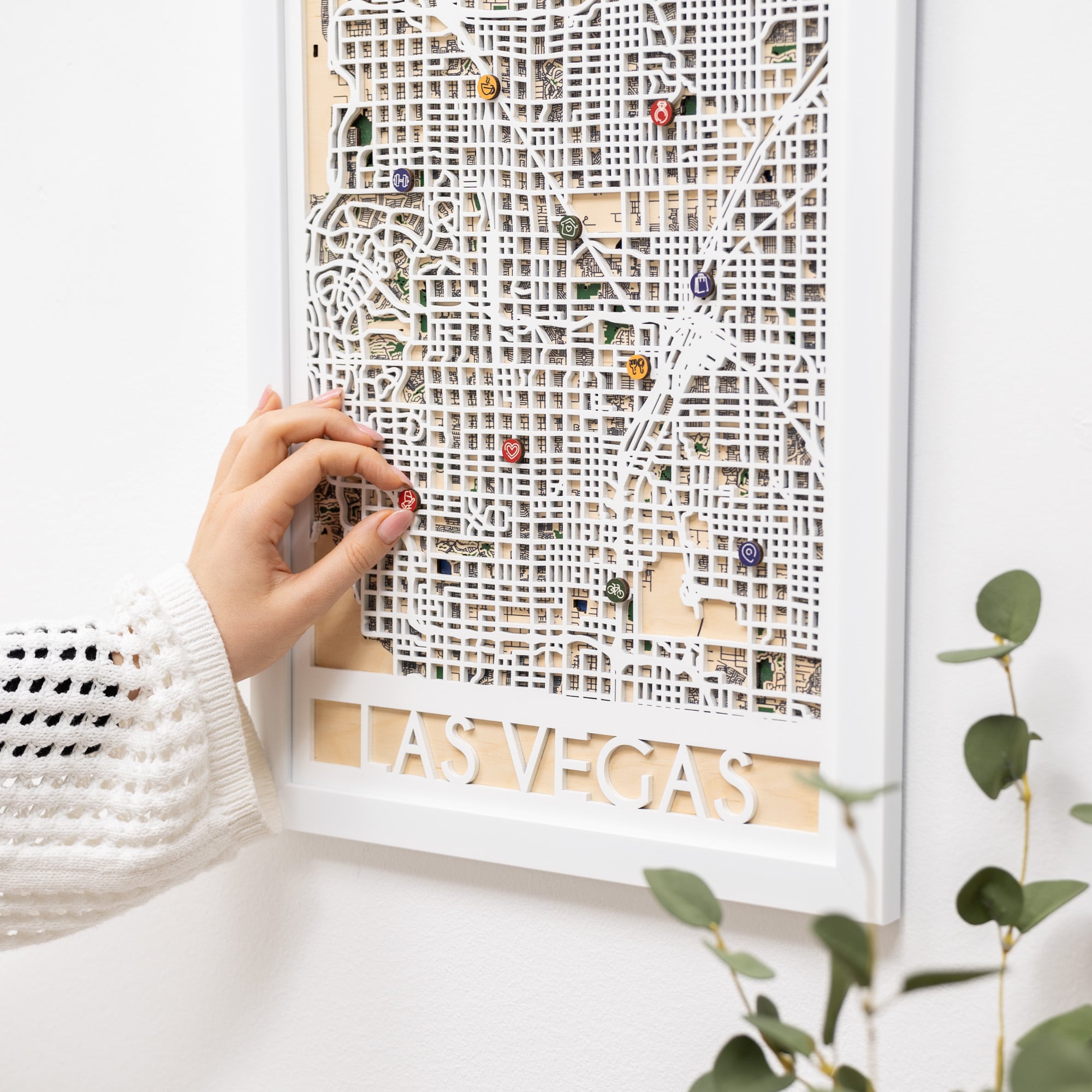 Framed city map of Las Vegas with decorative pins on a white wall.