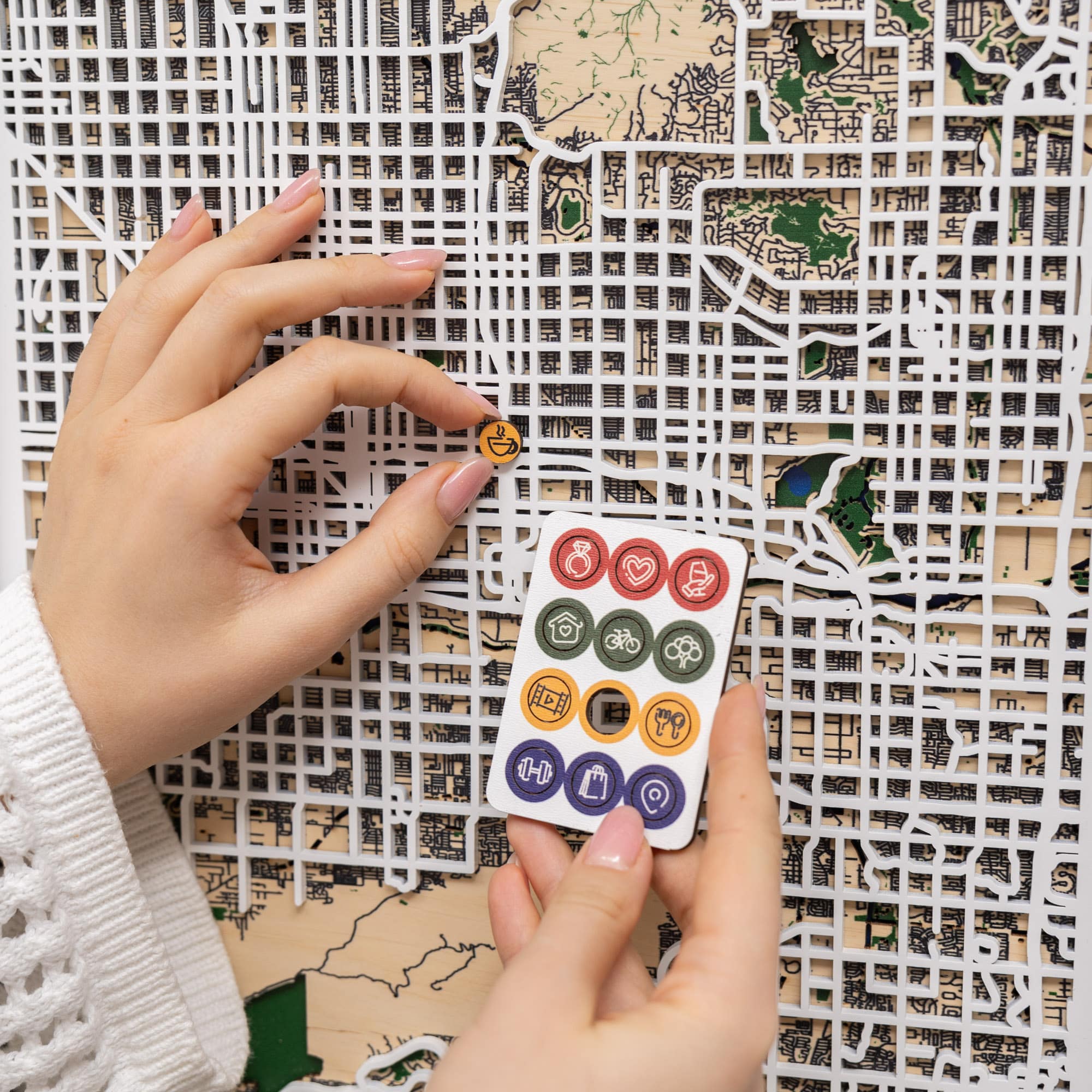 Hand holding a small white card with colorful icons against a textured background