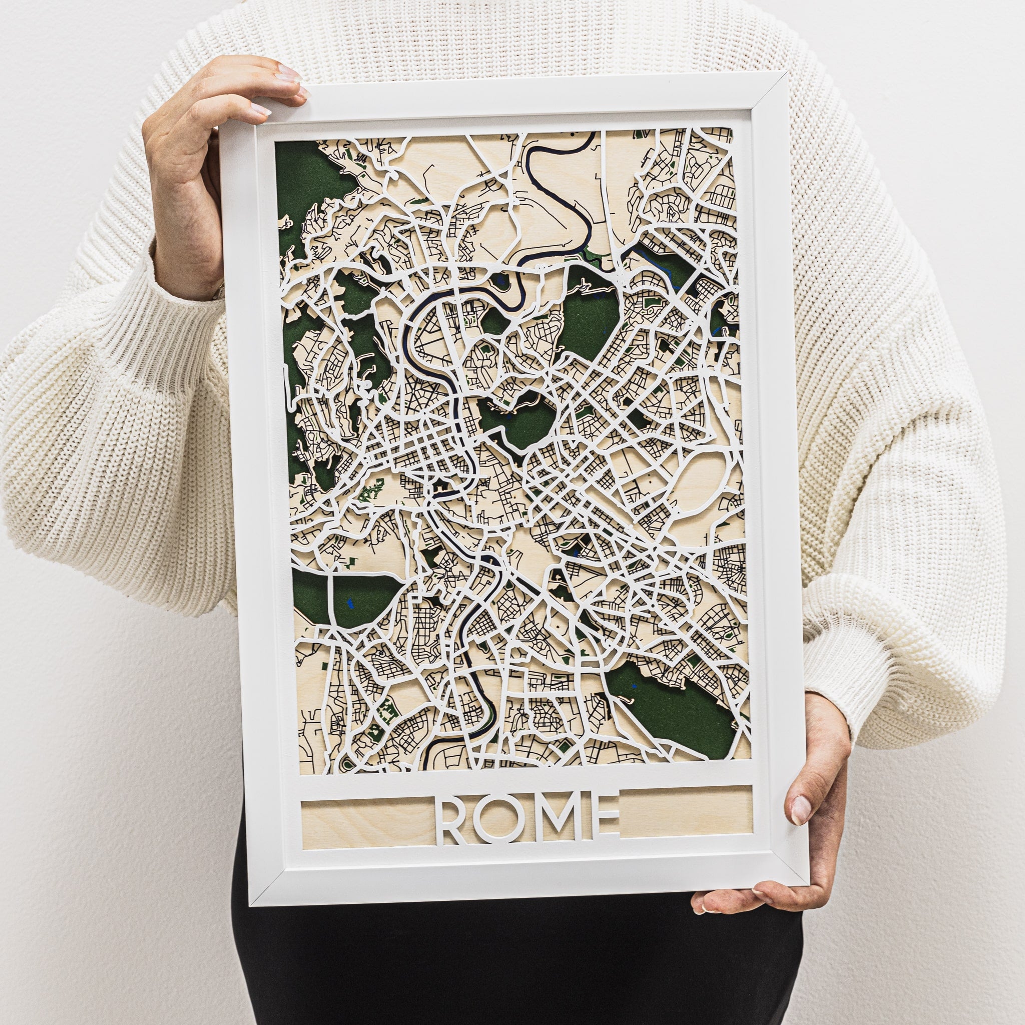 Person holding a framed 3D paper model of Rome's street map.