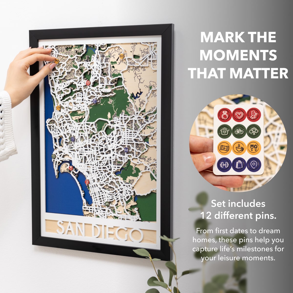 Framed map of San Diego with decorative pins on a white wall.