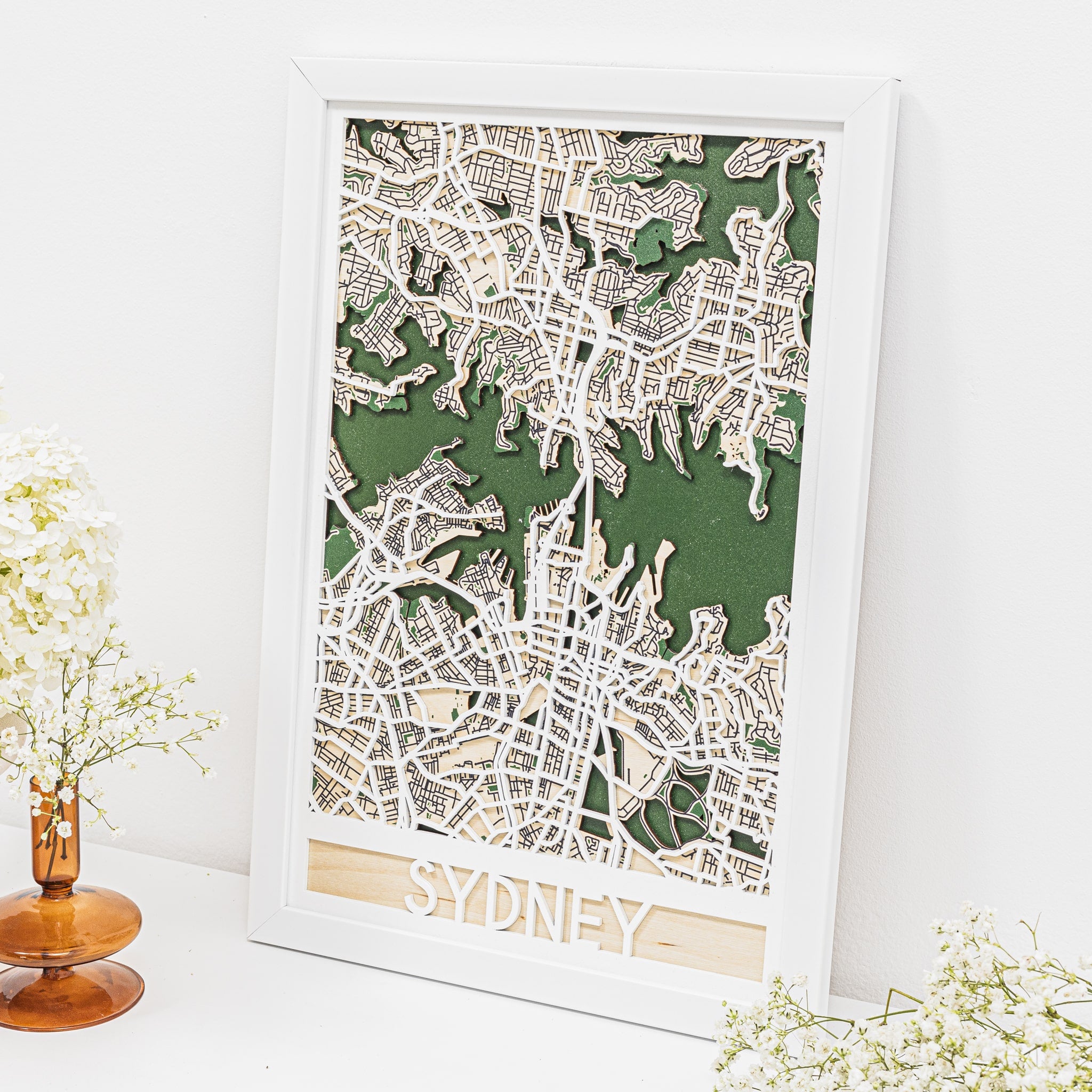Framed map of Sydney on a white surface with decorative elements.