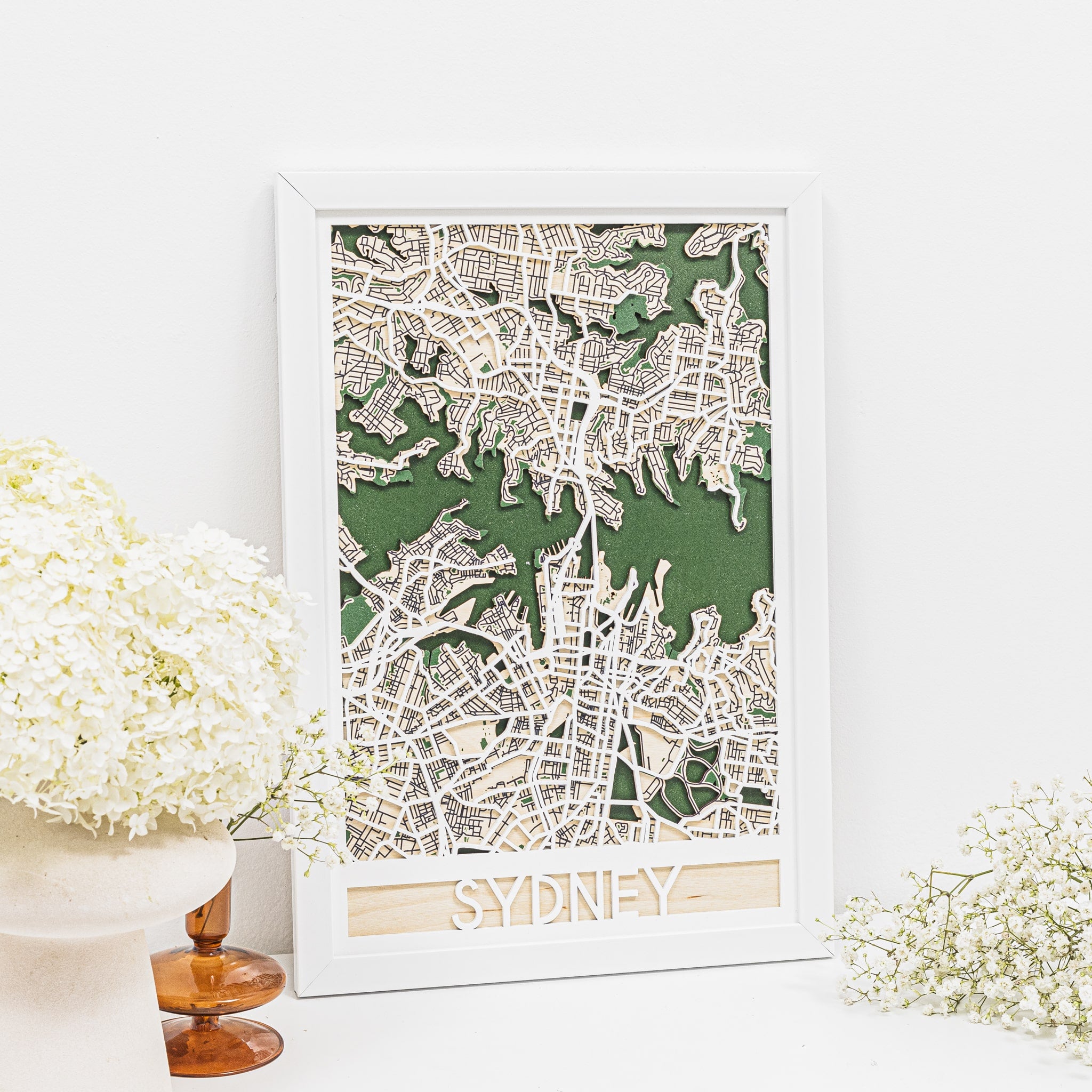 Framed map of Sydney on a white surface with decorative flowers.