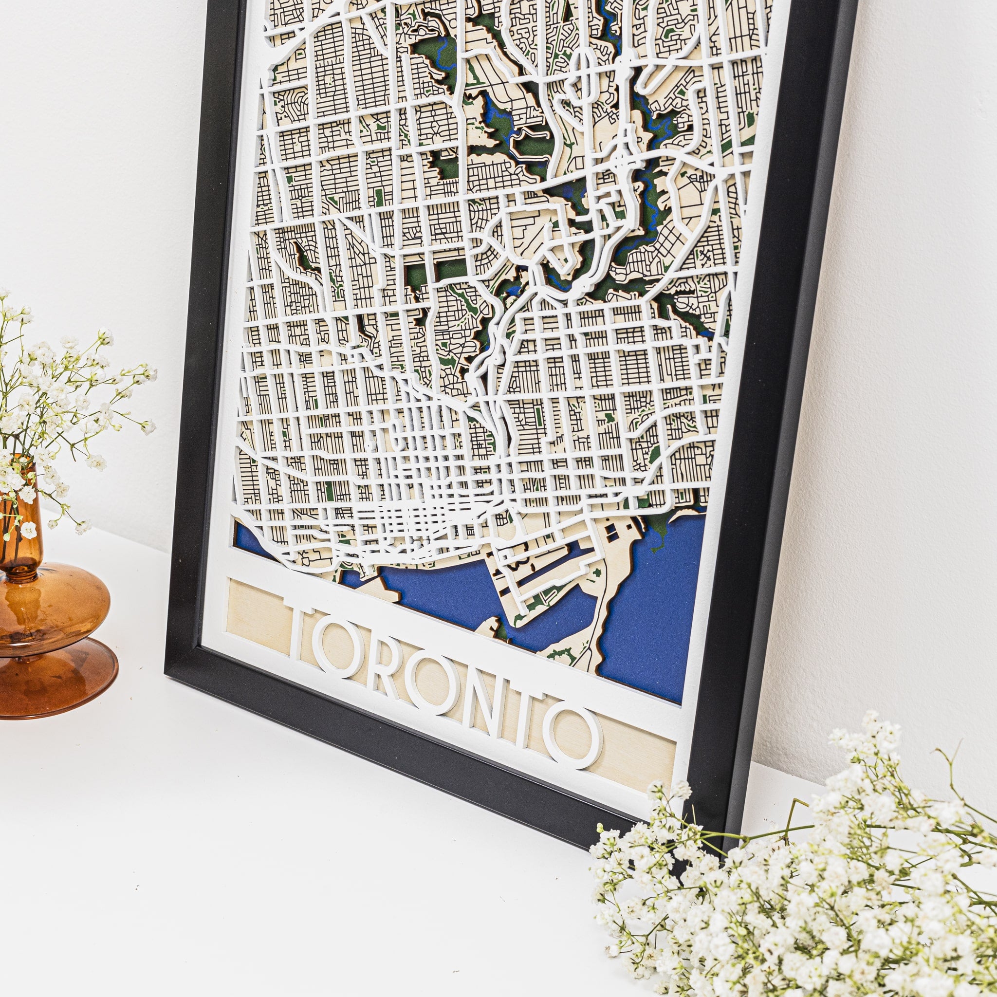 Framed map of Toronto on a white surface with decorative elements.