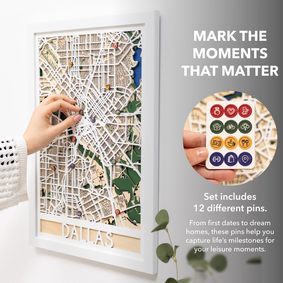 Woman hanging a framed map on a wall next to a wooden side table with books and a plant.
