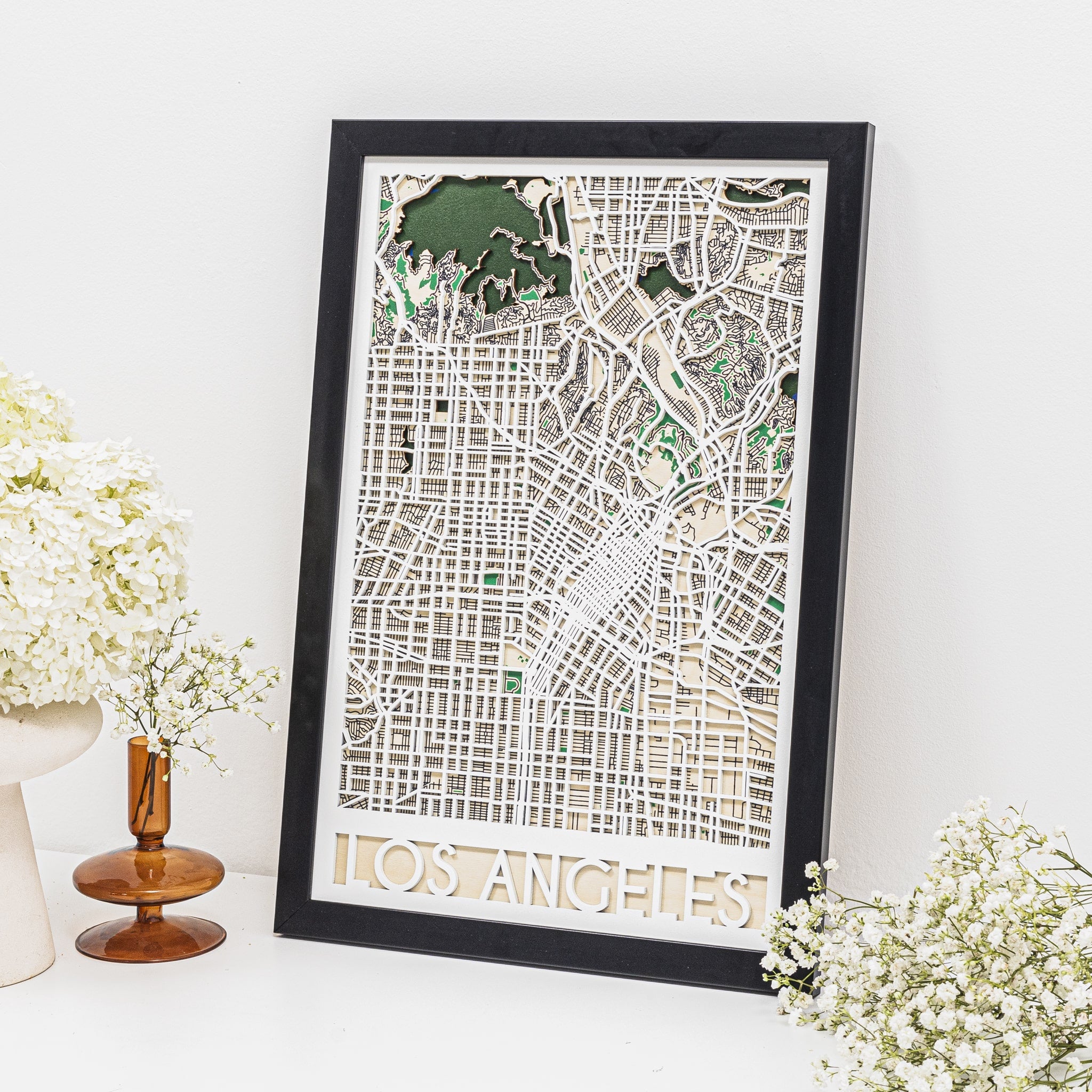 Framed map of Los Angeles on a white surface with decorative flowers.
