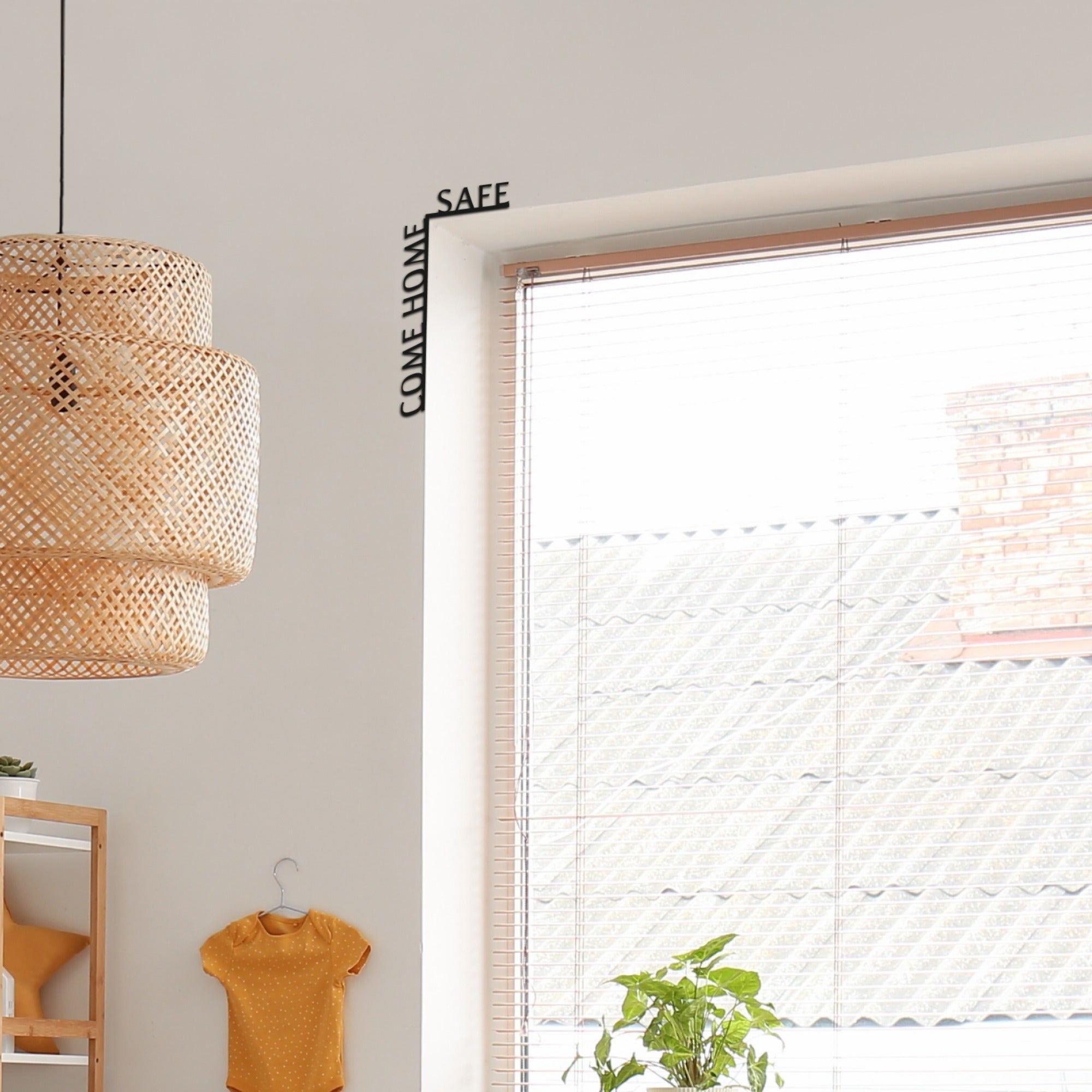 Room interior with a woven lampshade, hanging shirt, plant, and decorative wall art.