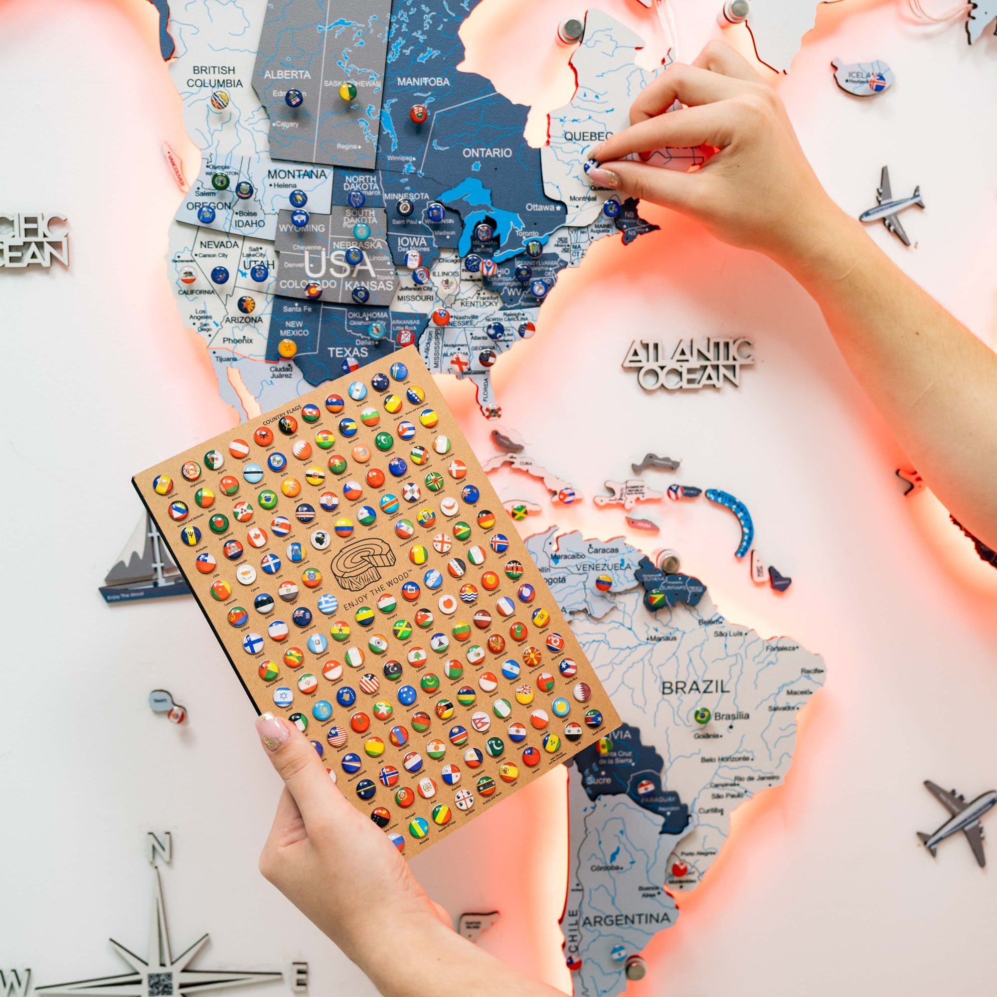 Map of the world with pins and a notebook held by hands against a map background