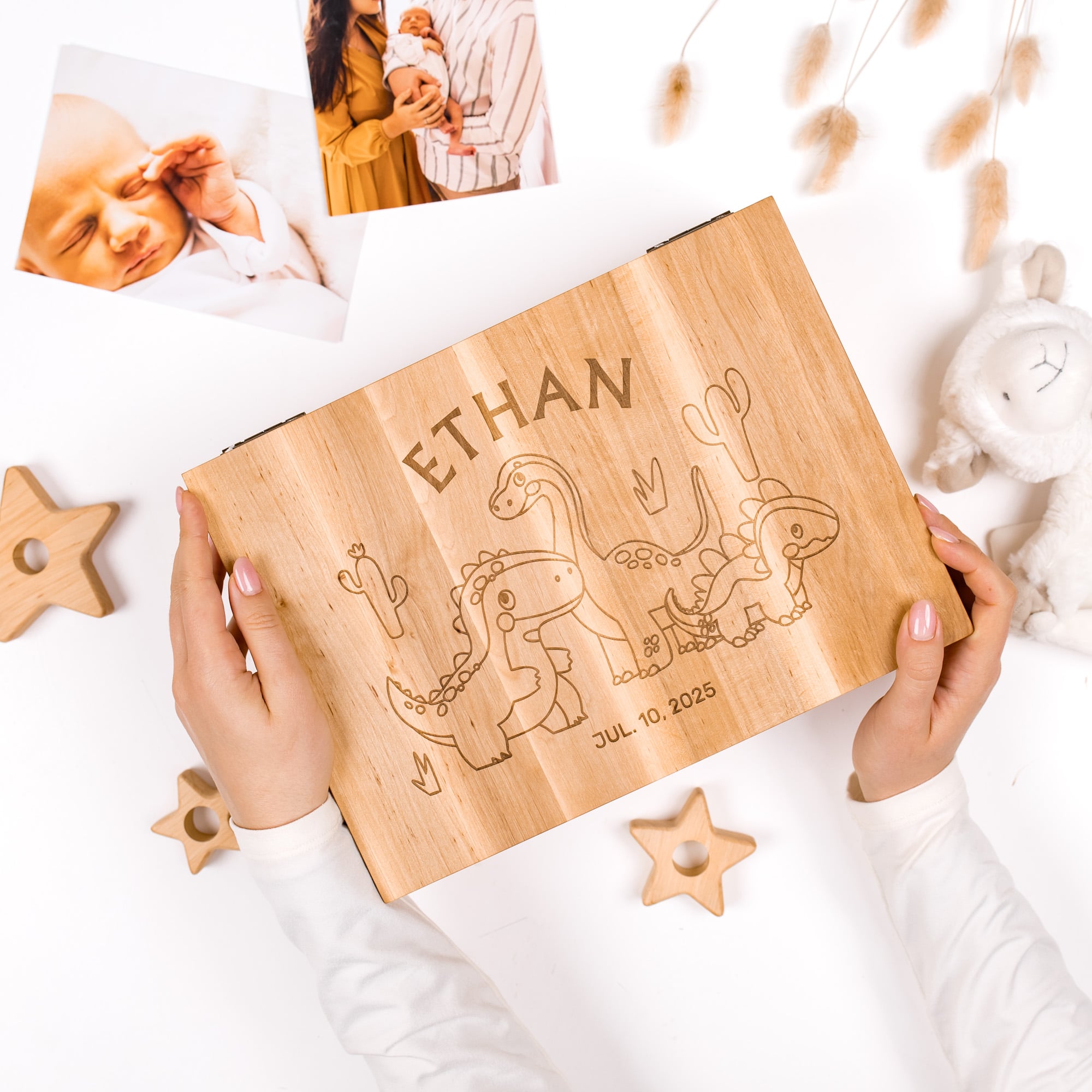 Wooden plaque with engraved names and dates, held by hands on a white surface with decorative items.