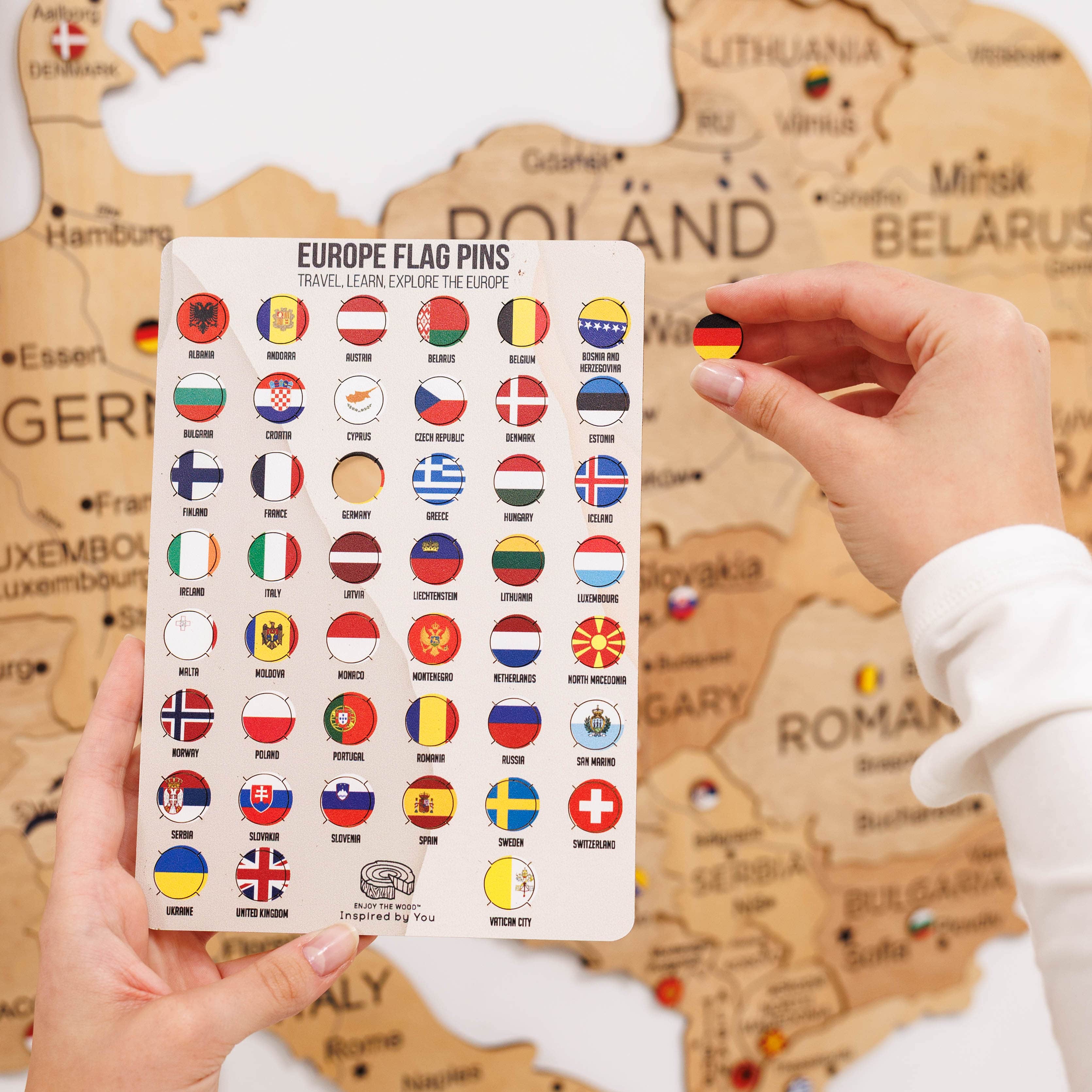 Card with European flag pins held by a hand in front of a map background