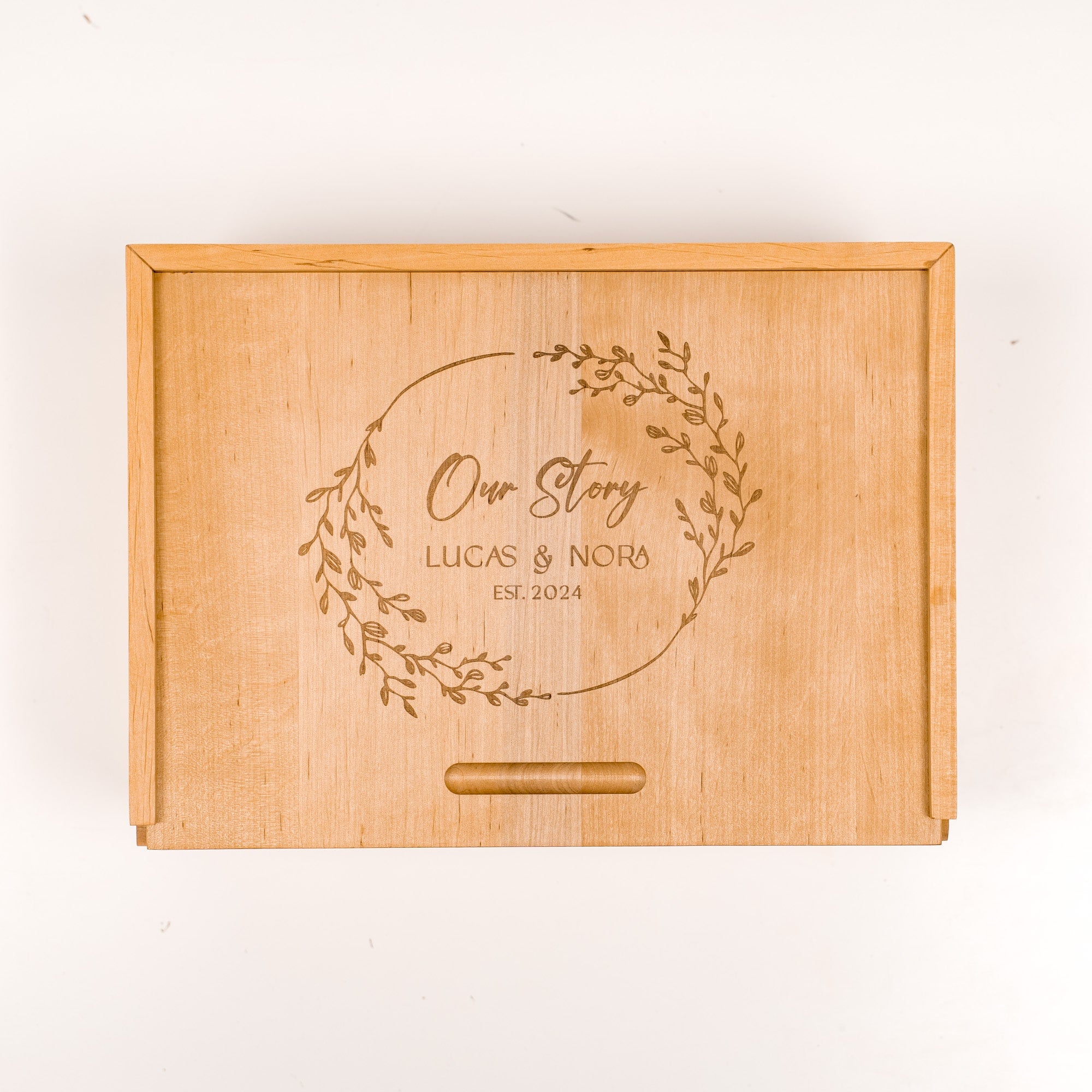 Wooden box with engraved text 'Our Story Lucas & Nora Est. 2024' on a white background