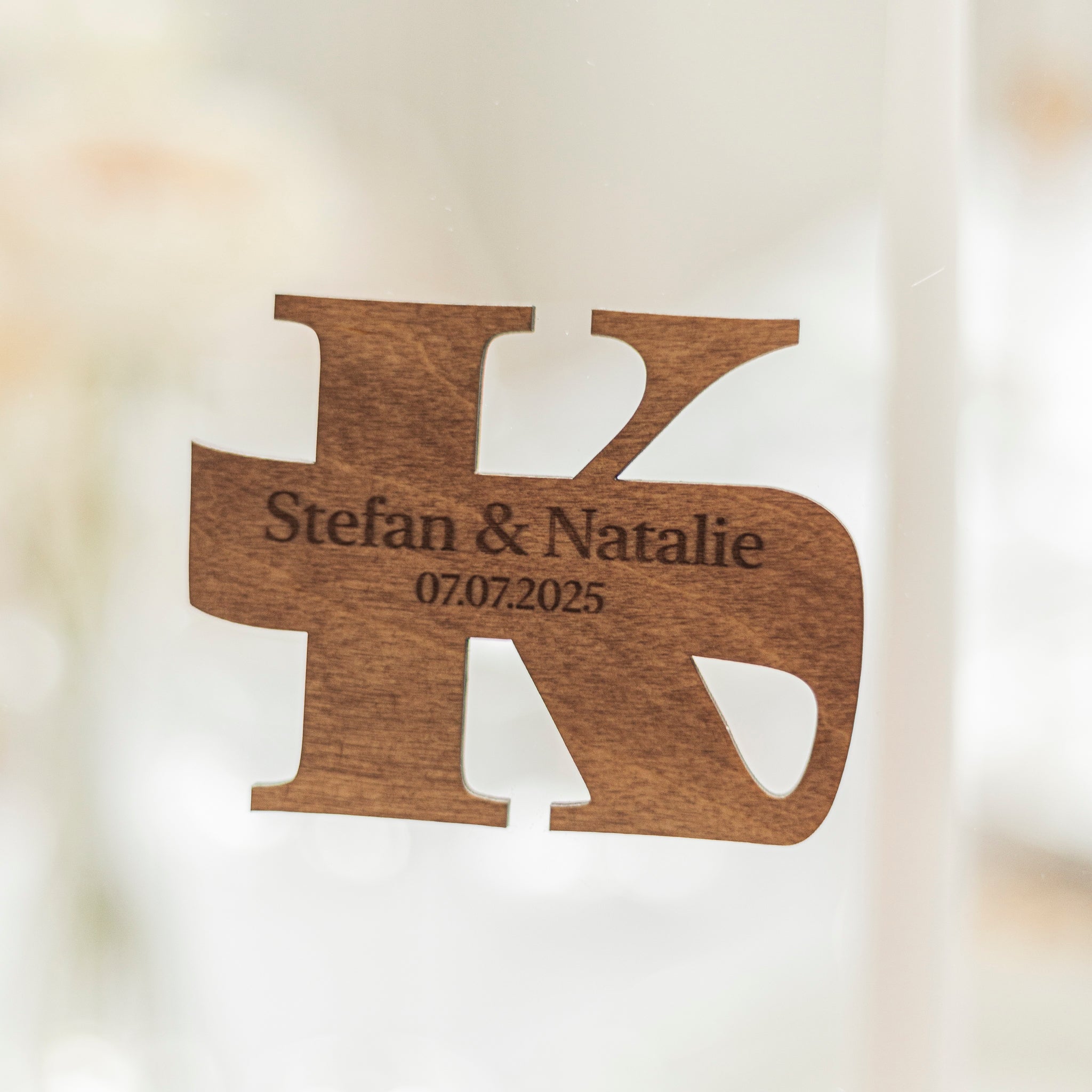 Wooden decorative item with 'Stefan & Natalie' and date engraved on a blurred background
