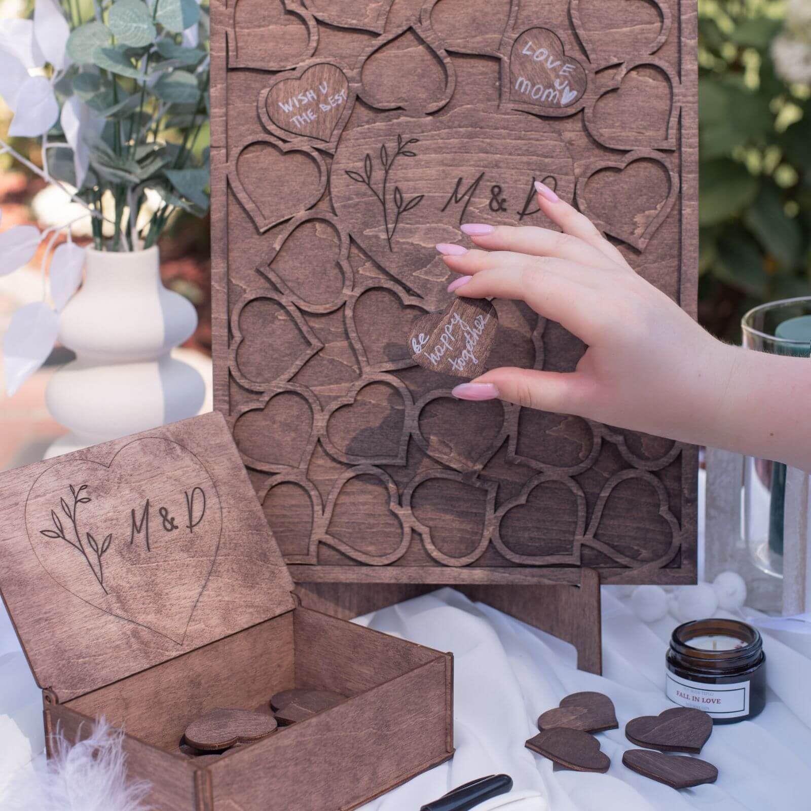 Hand placing wooden heart message into rectangular guest book frame
