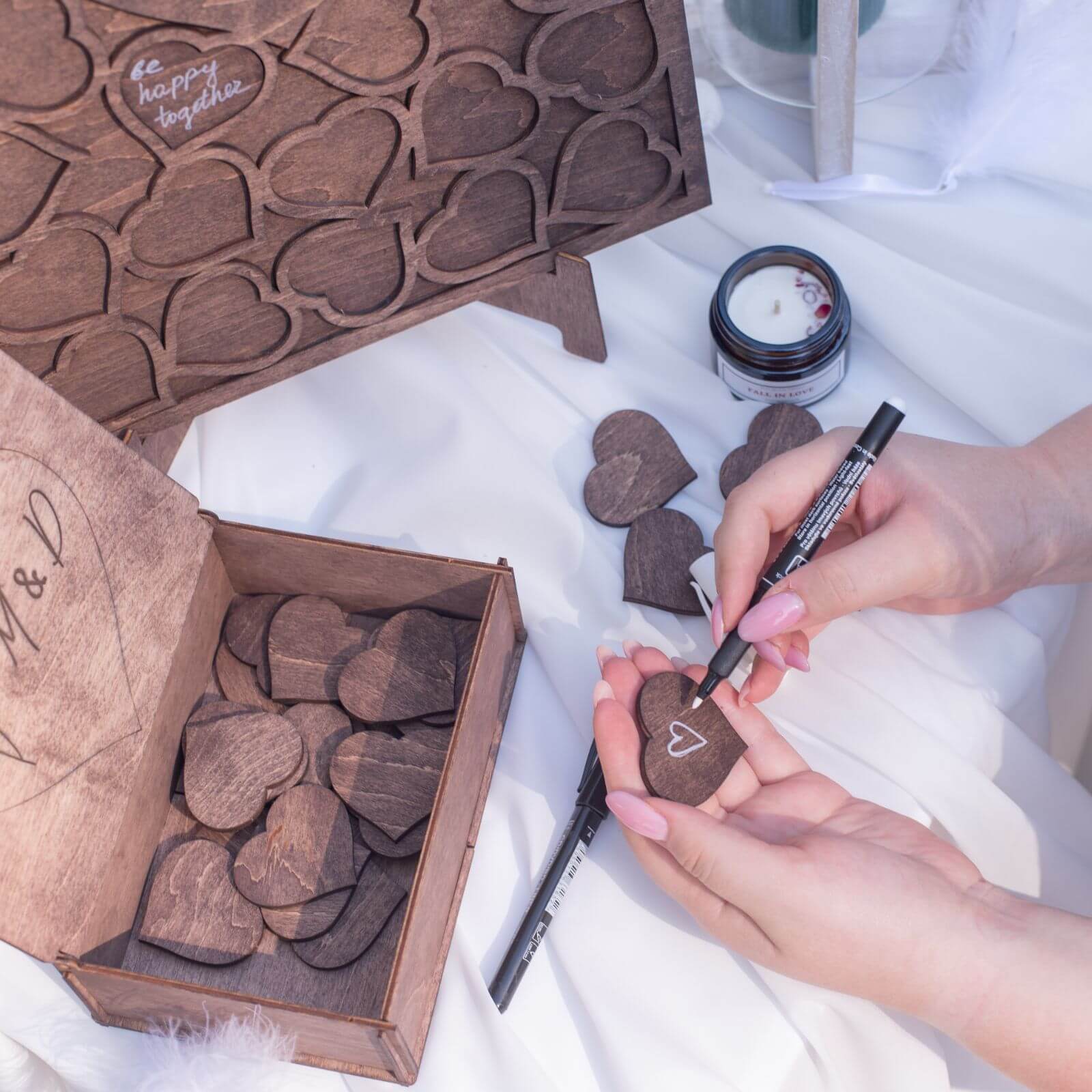 Writing on wooden heart piece with white marker for guest book