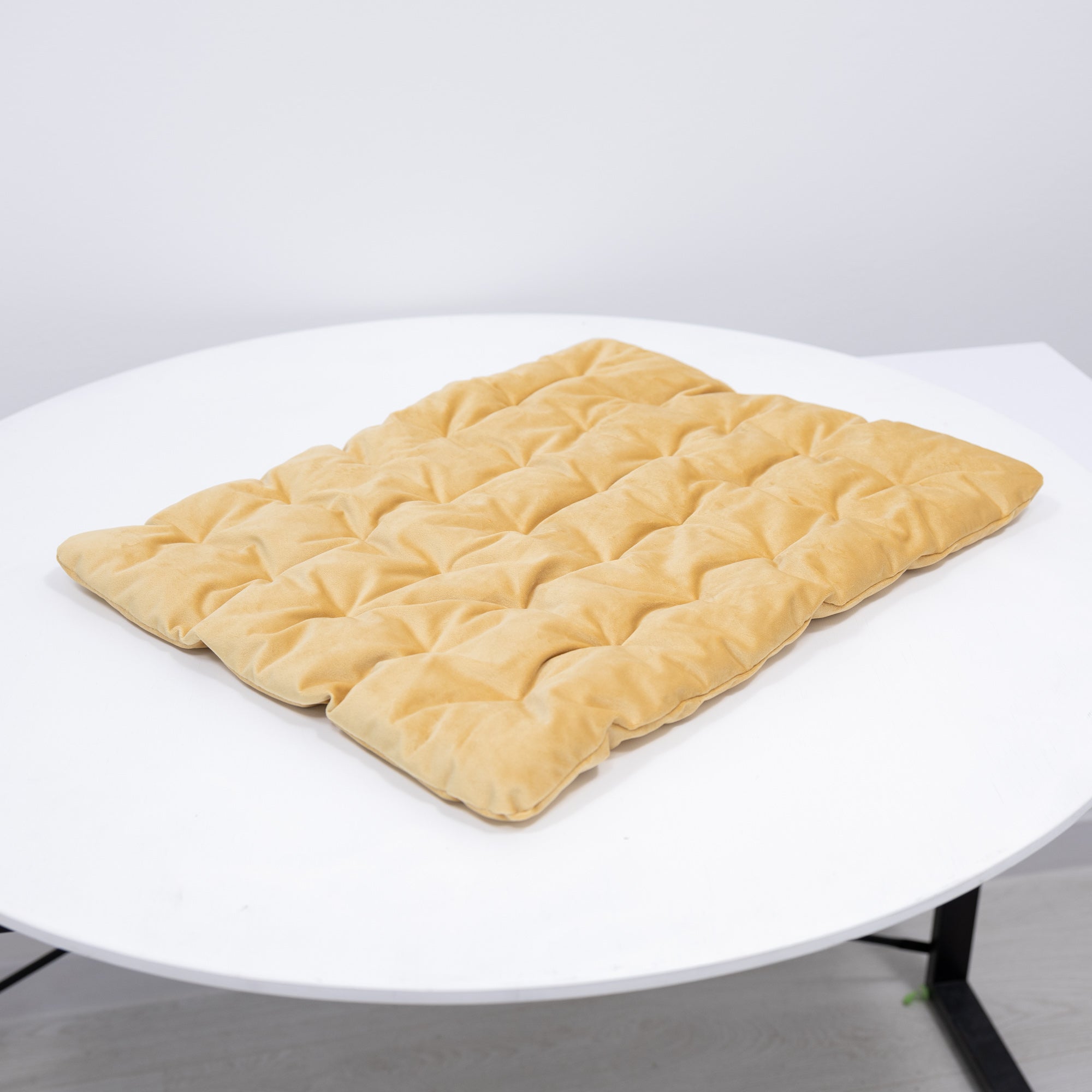 Beige quilted mat on a white round table with a light gray background