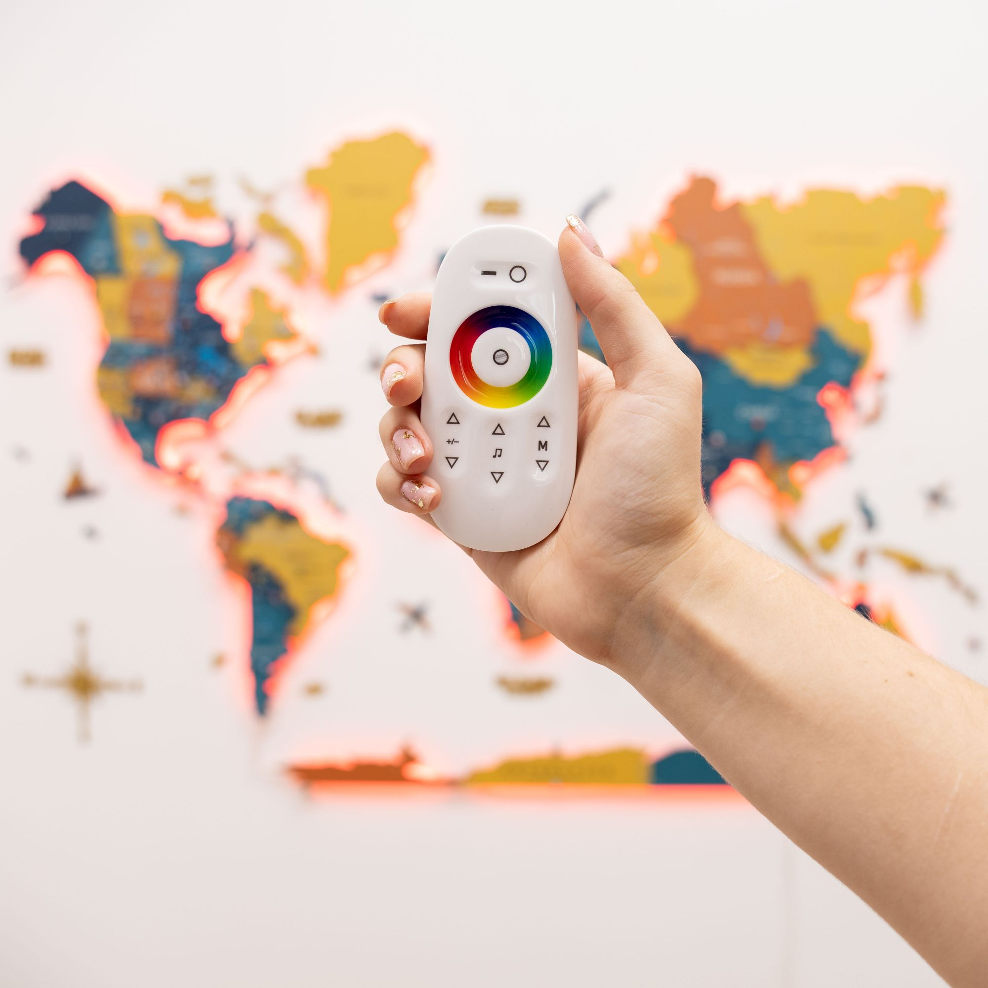 Hand holding a remote control with a world map in the background
