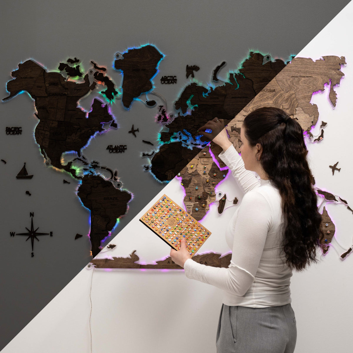 Woman interacting with a world map display on a wall.