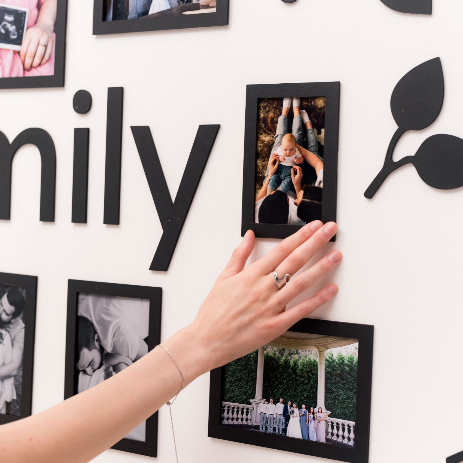 Modern wall photo collage with family pictures in black frames.