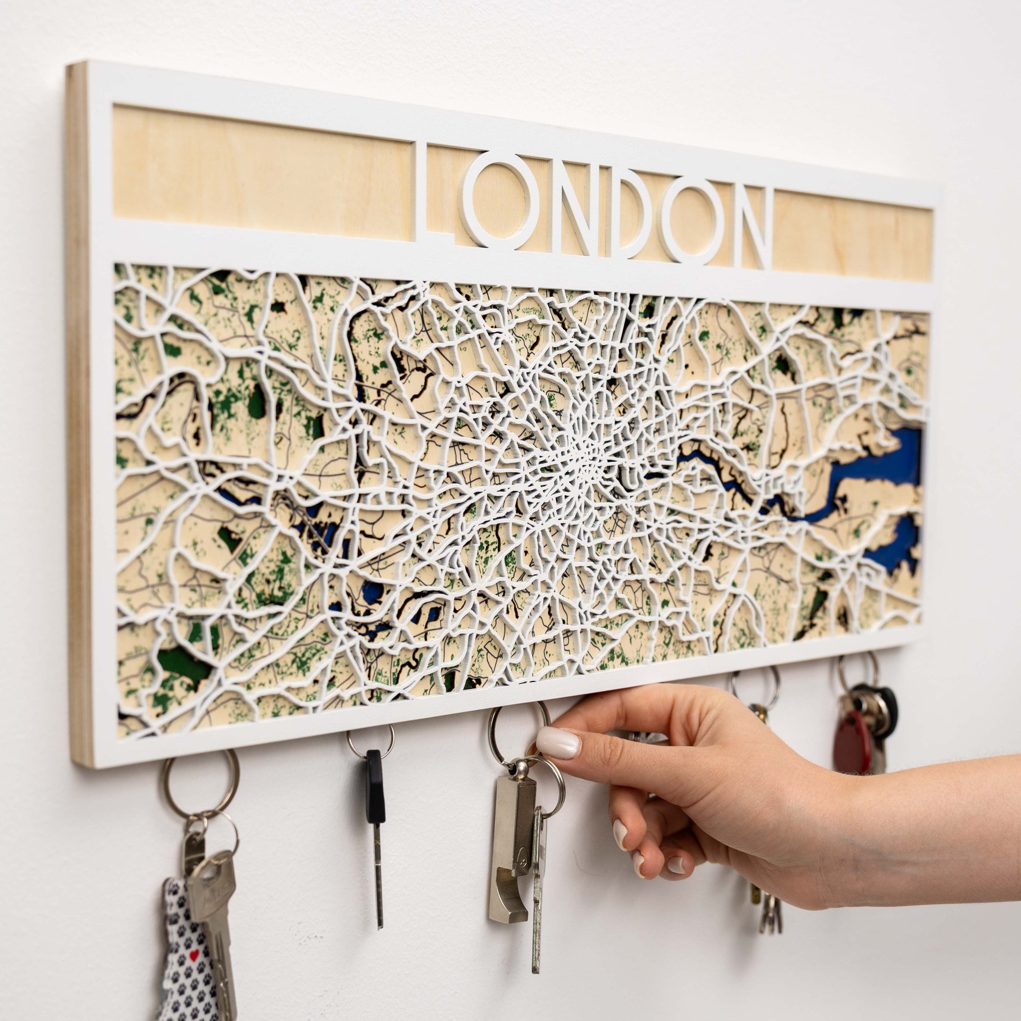 Key holder with a map of London and a hand hanging keys on it.