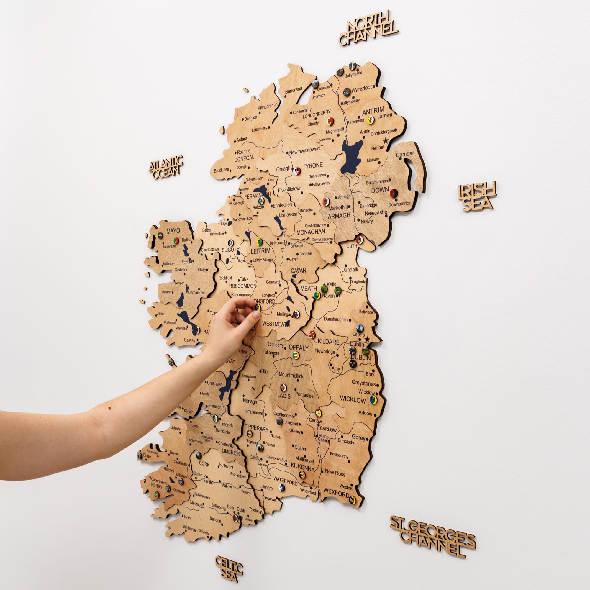 Wooden map of Ireland with a hand pointing to a location on a white background