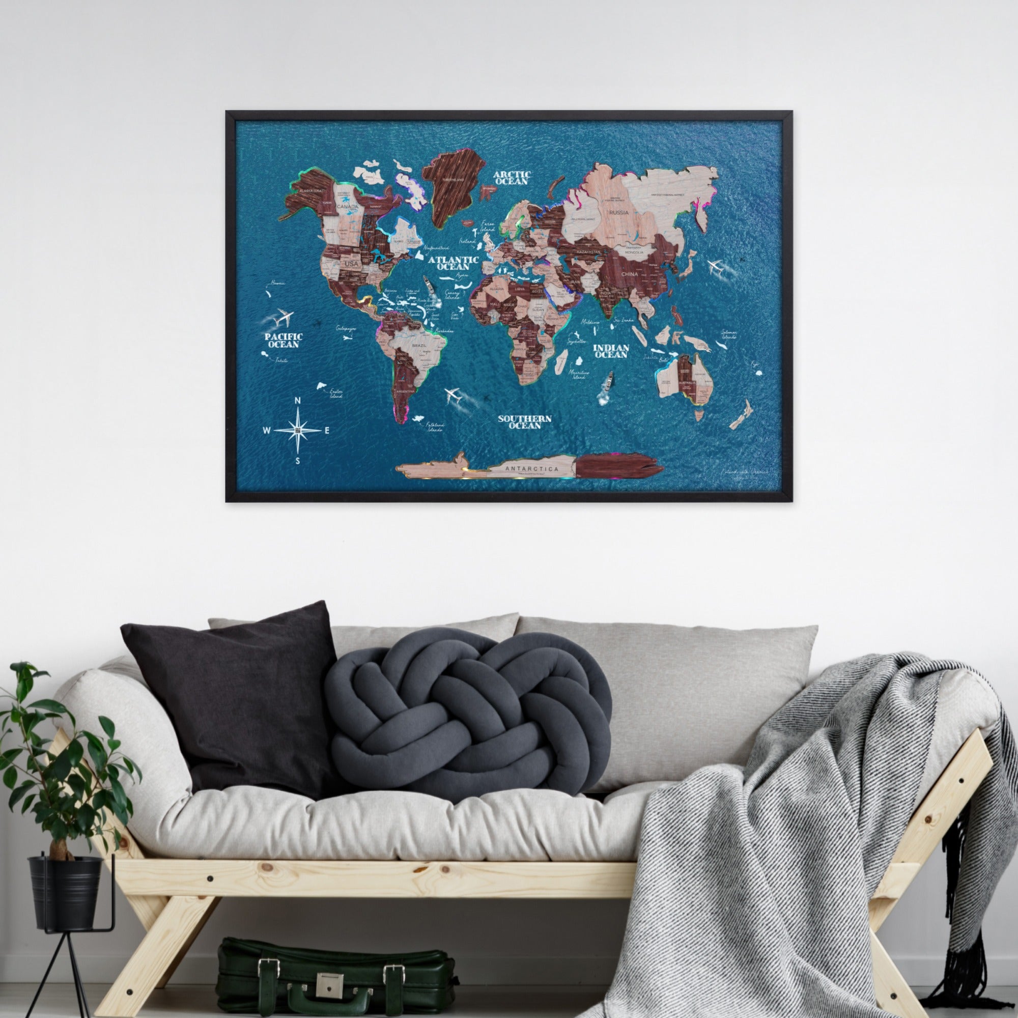 World map poster on a wall above a sofa with decorative pillows and a blanket.