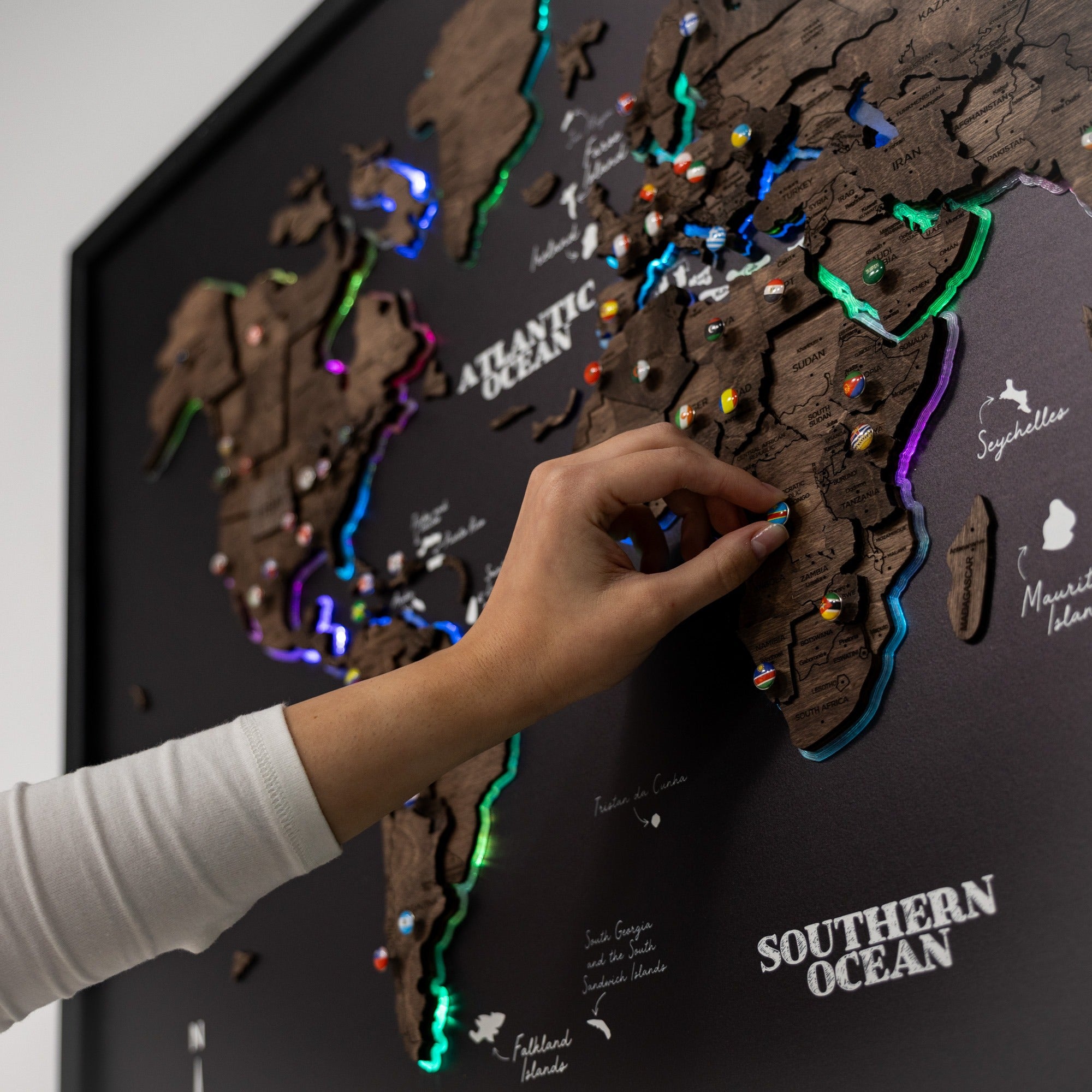 Hand interacting with a world map puzzle on a dark surface