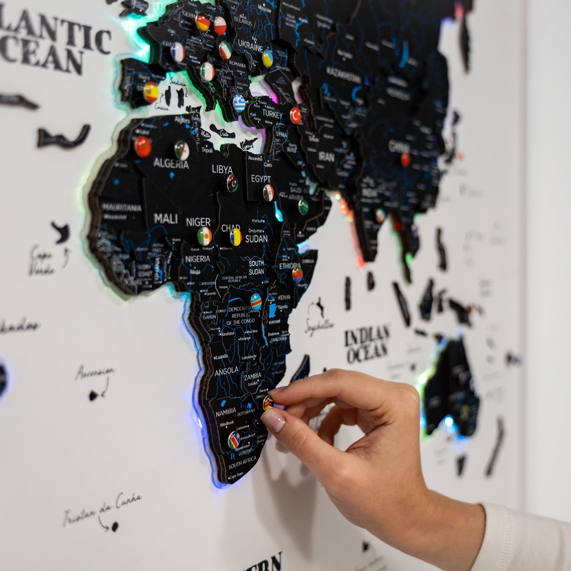 Hand interacting with a map of Africa on a wall, with colorful pins indicating locations.