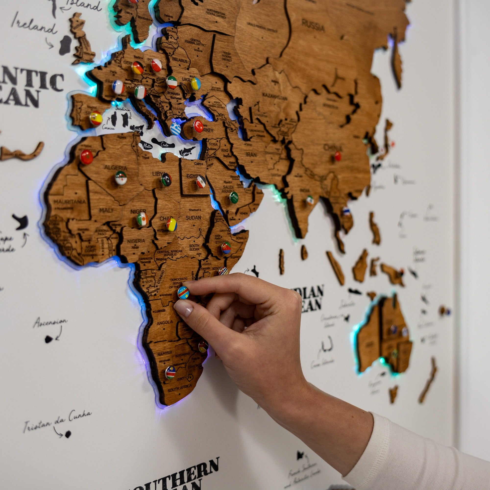 Wooden world map with LED lights and pins on a white background