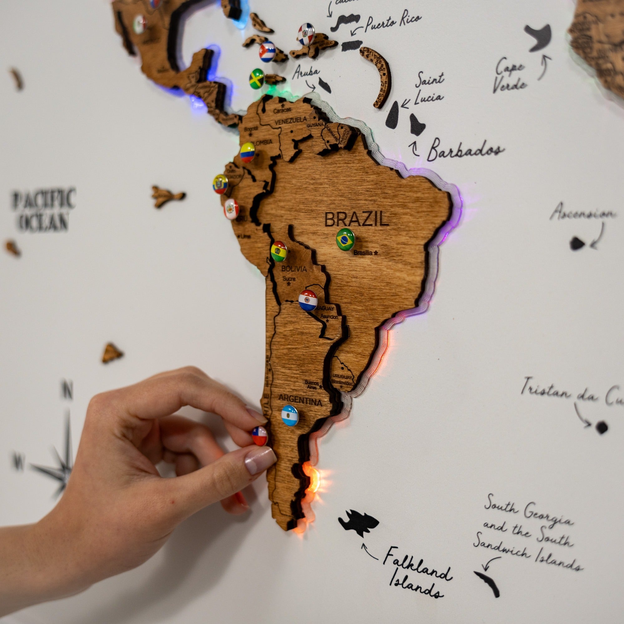 Wooden map of South America with LED lights and pins marking locations.