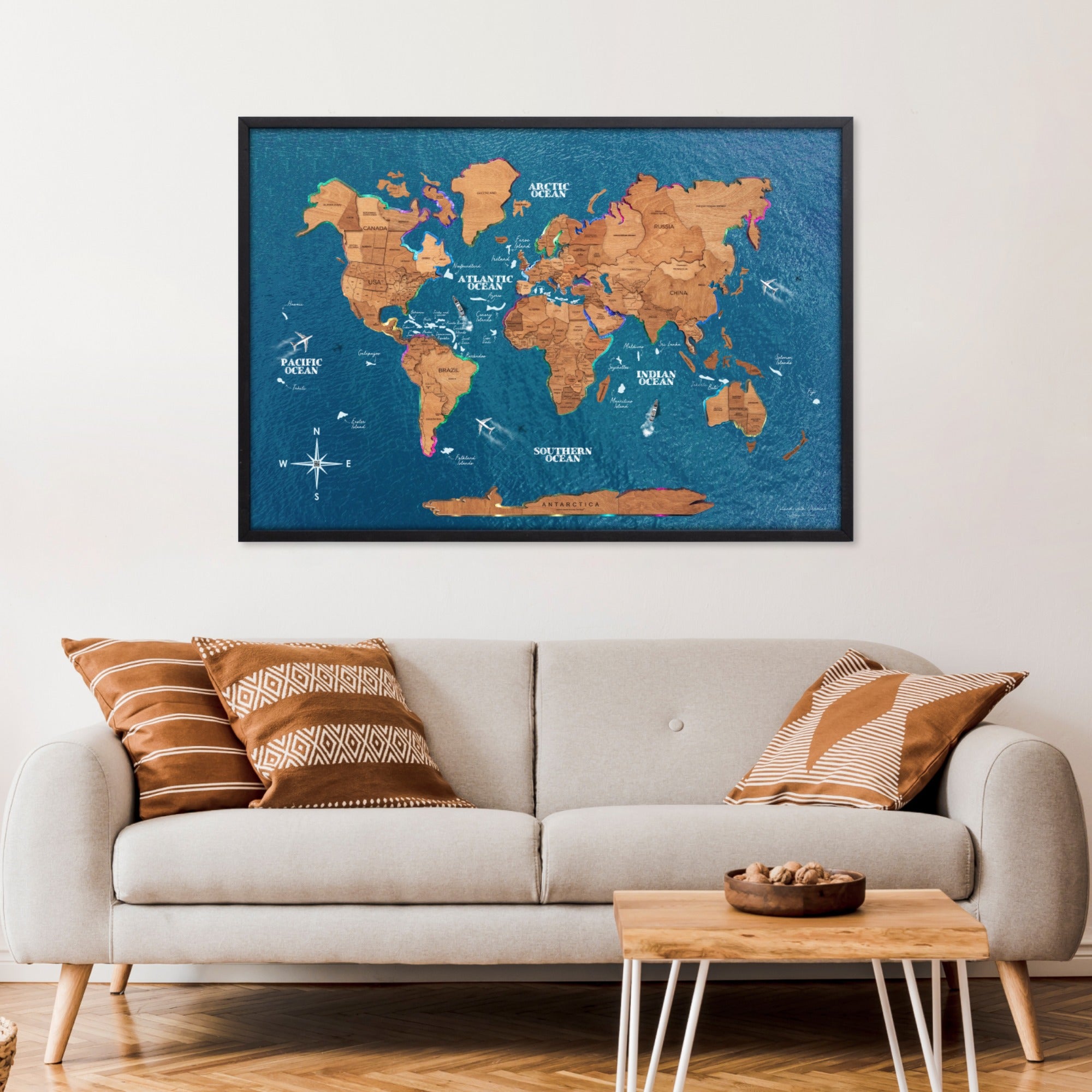 World map poster on a wall above a sofa with decorative pillows.