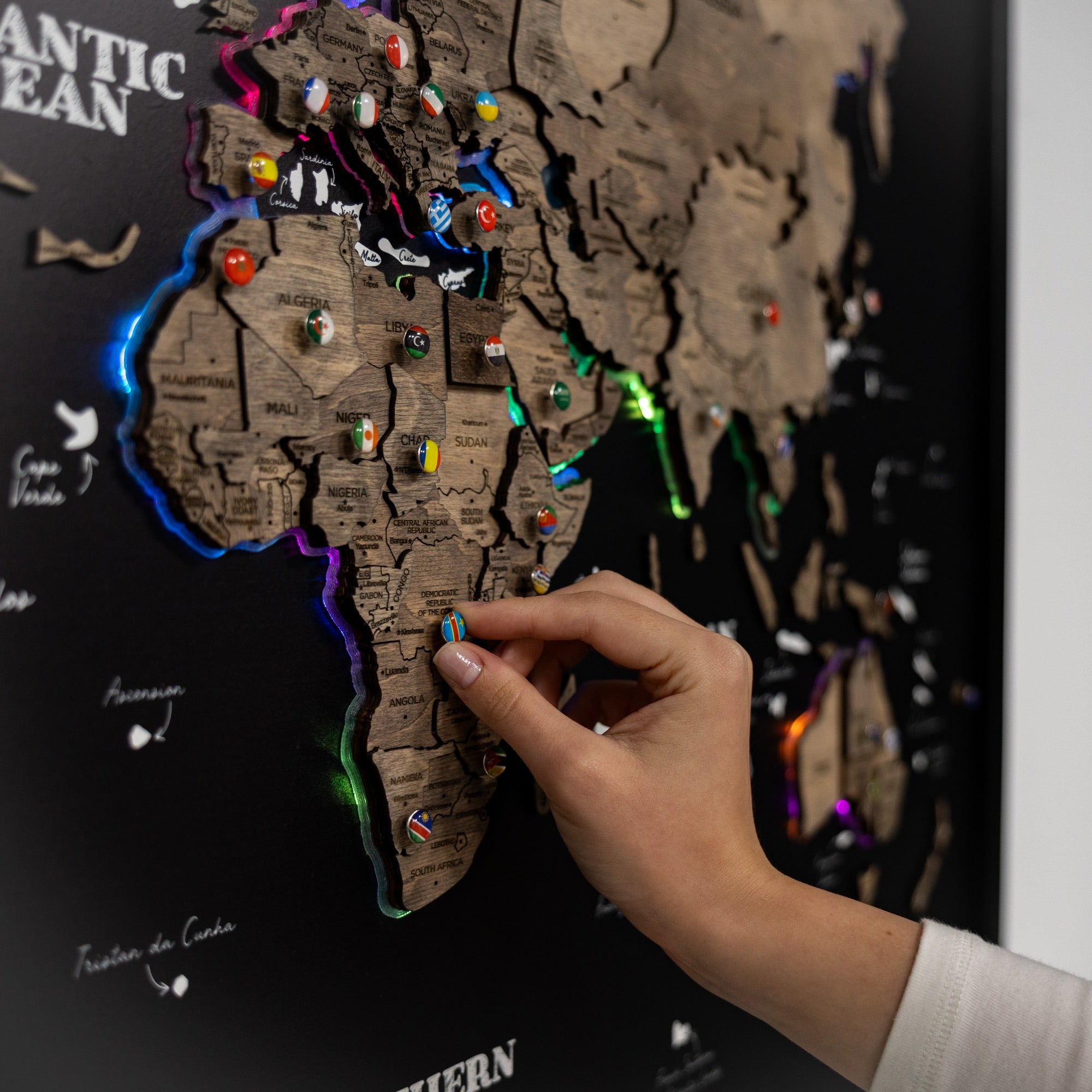 Hand placing a marker on a world map with colorful pins.